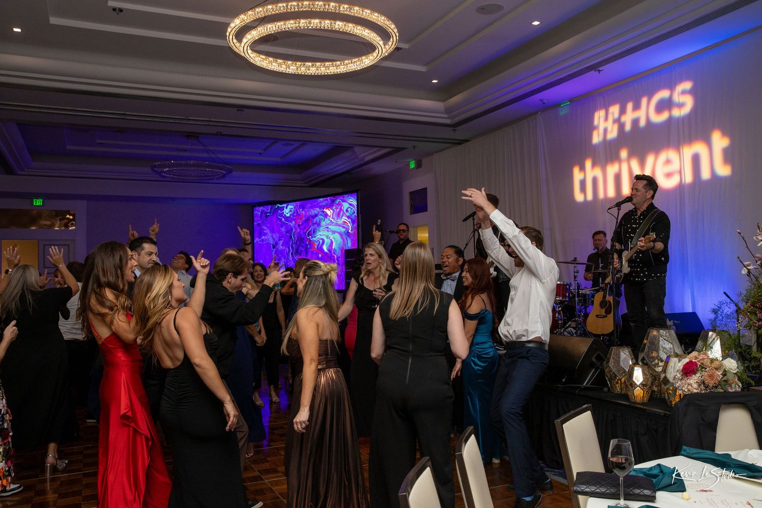 Guests dancing at an HCS Thrivent corporate gala event with live band performance and purple ambient lighting.