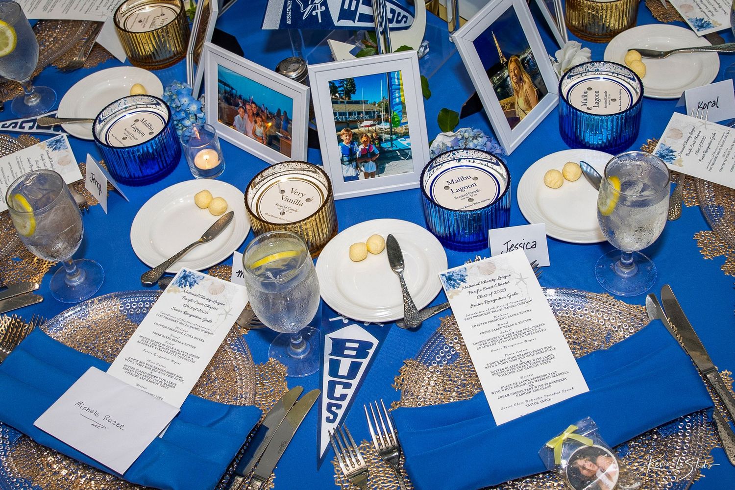 Blue and gold Duke University themed table setting with pennant, framed photos, blue candles, and elegant place settings.