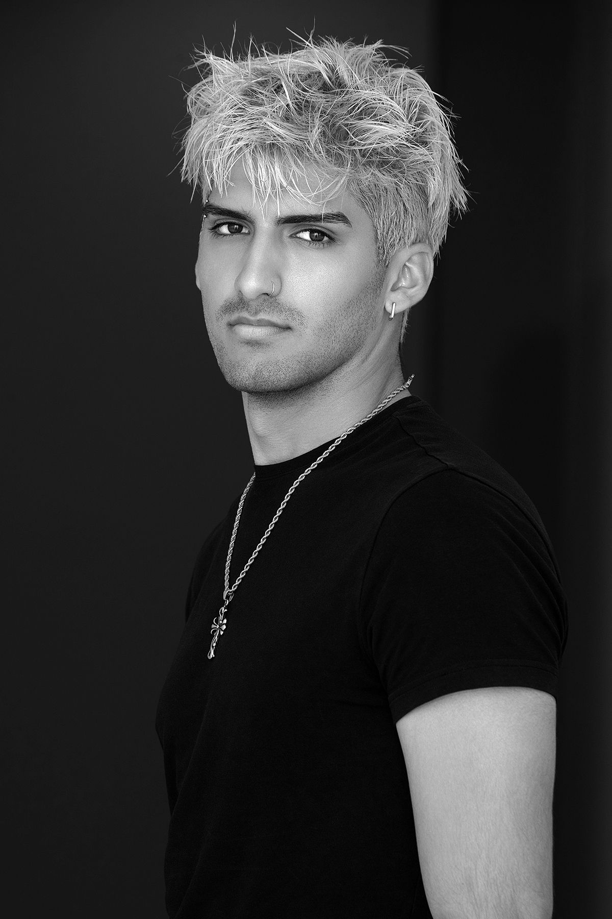 Black and white portrait of a young man with bleached spiky hair wearing a black t-shirt.