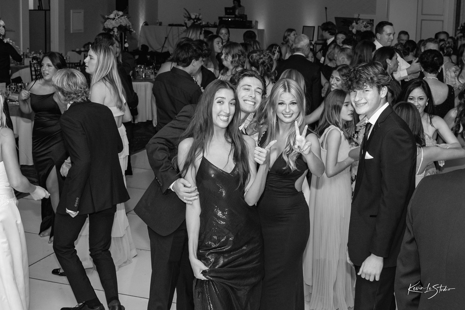 Black and white photo of elegantly dressed guests posing and smiling at a formal gala event.