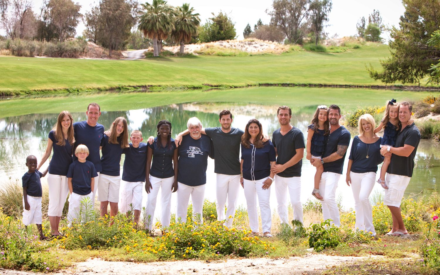 Large extended family group poses together in matching navy and white outfits on a golf course.