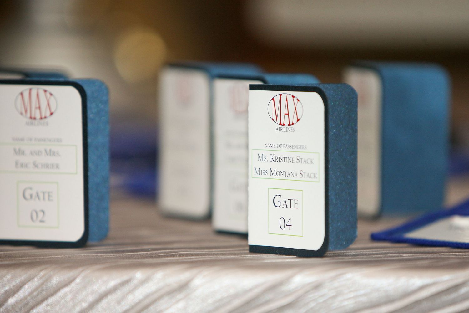Elegant wedding place cards with gate numbers displayed in blue fabric holders on a decorated table.