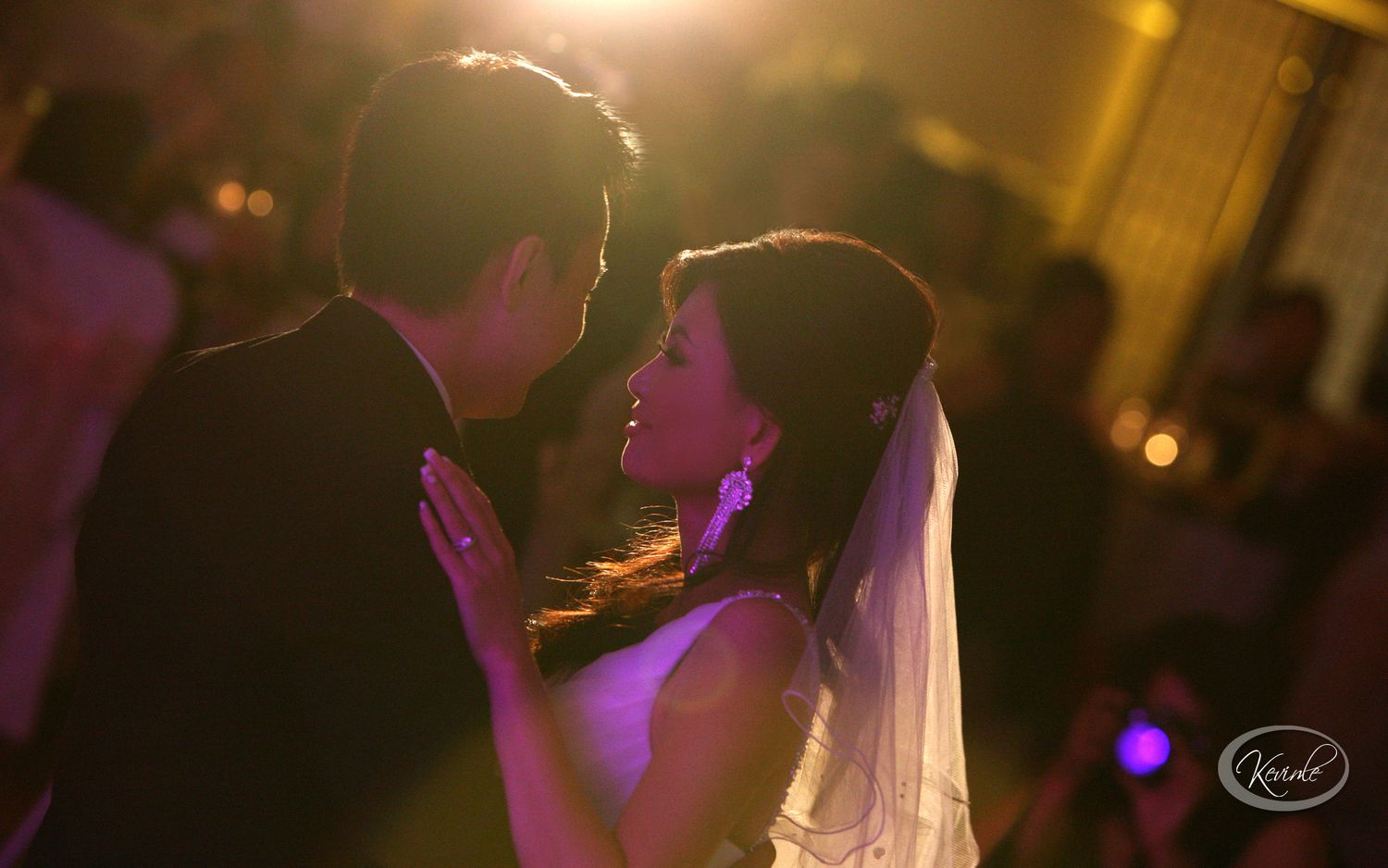 A bride and groom share an intimate first dance moment, bathed in warm golden light at their wedding reception.