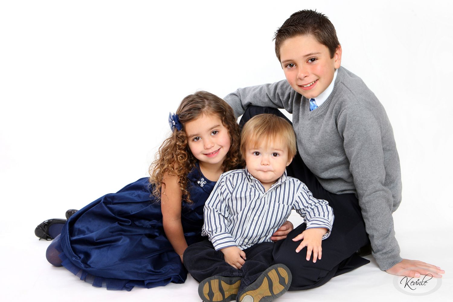 Three siblings posing together for a formal portrait on white background.
