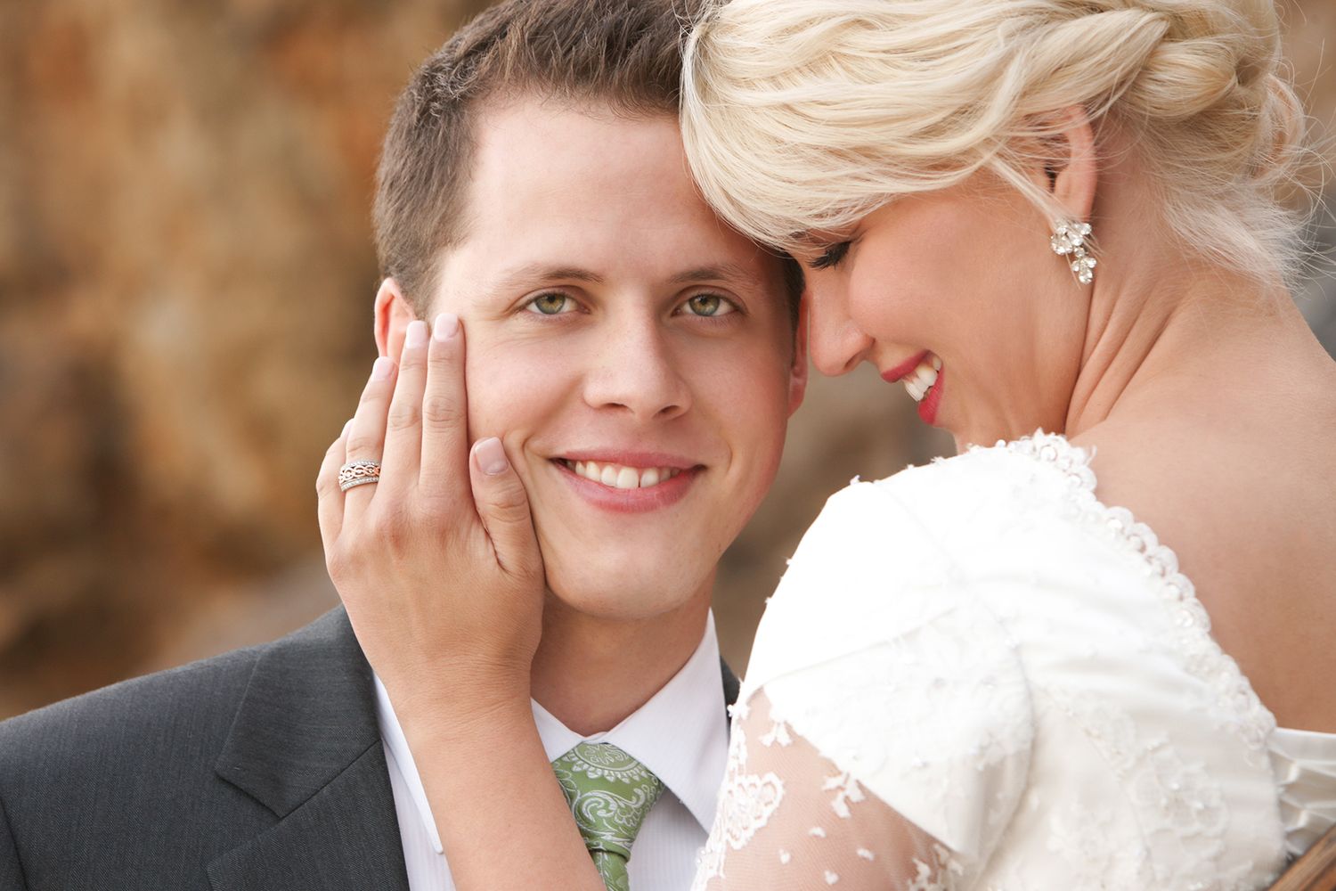 Smiling groom with bride leaning her head against his in a romantic portrait.