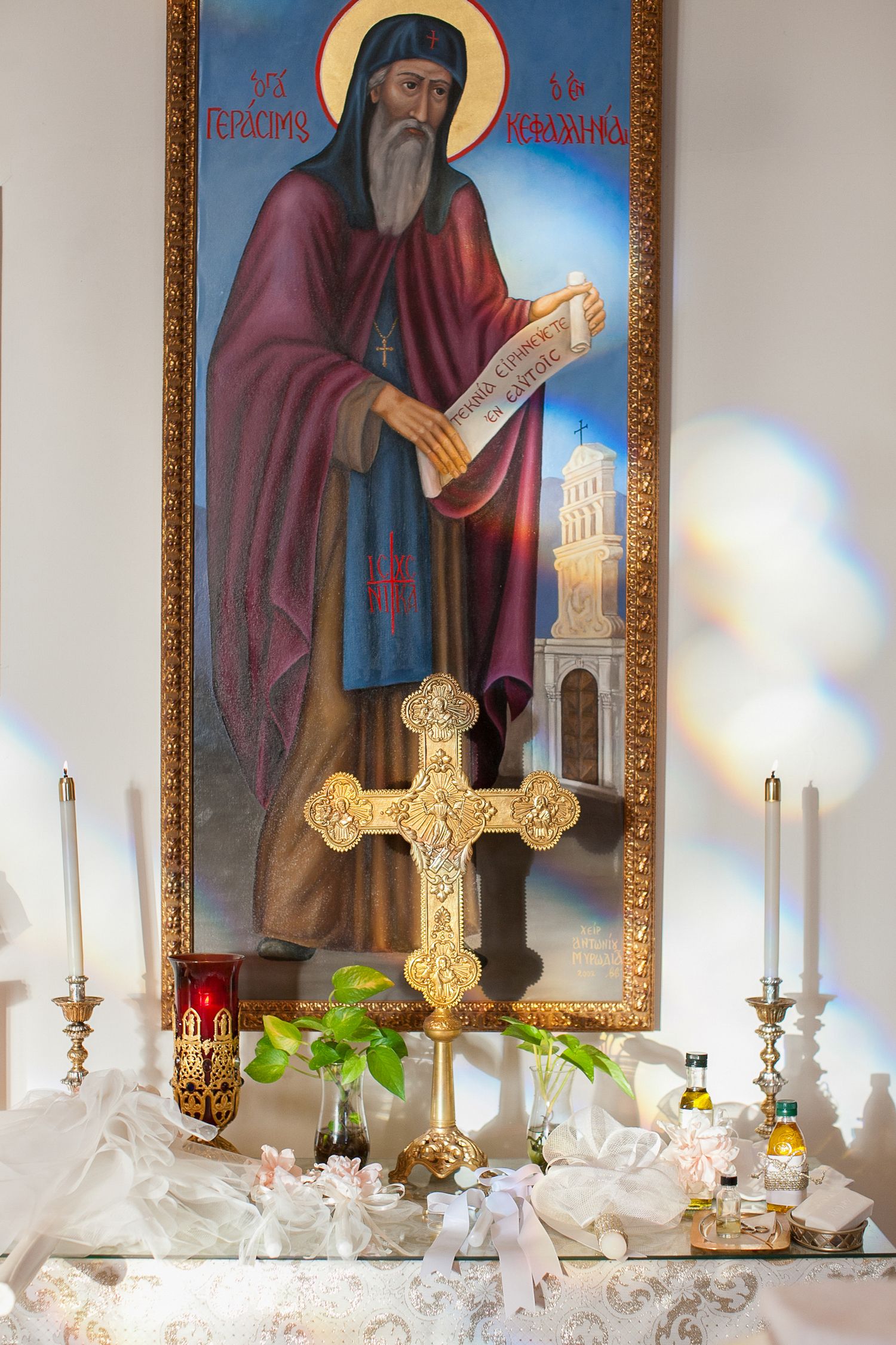 Orthodox Christian altar with golden cross, candles, and icon painting of a saint in a church.