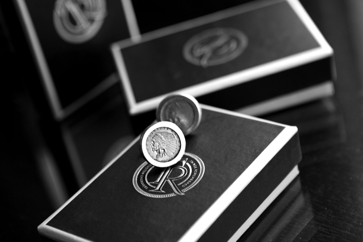 Black and white close-up of elegant silver cufflinks displayed on dark gift boxes.