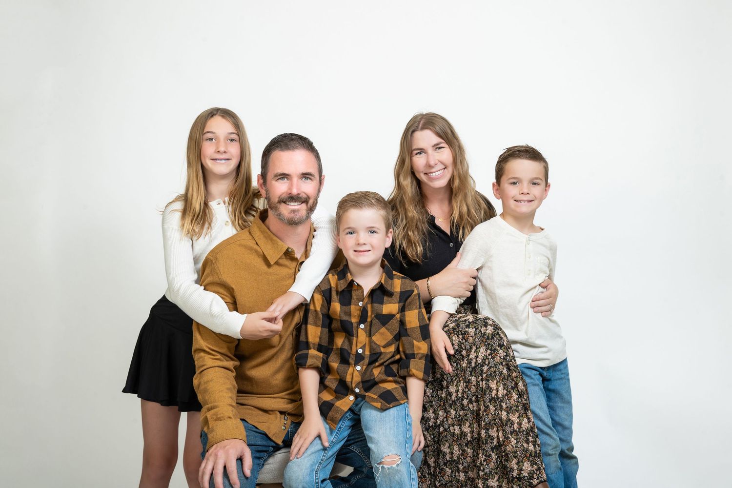 Family of five posing together for a professional portrait against a white background.