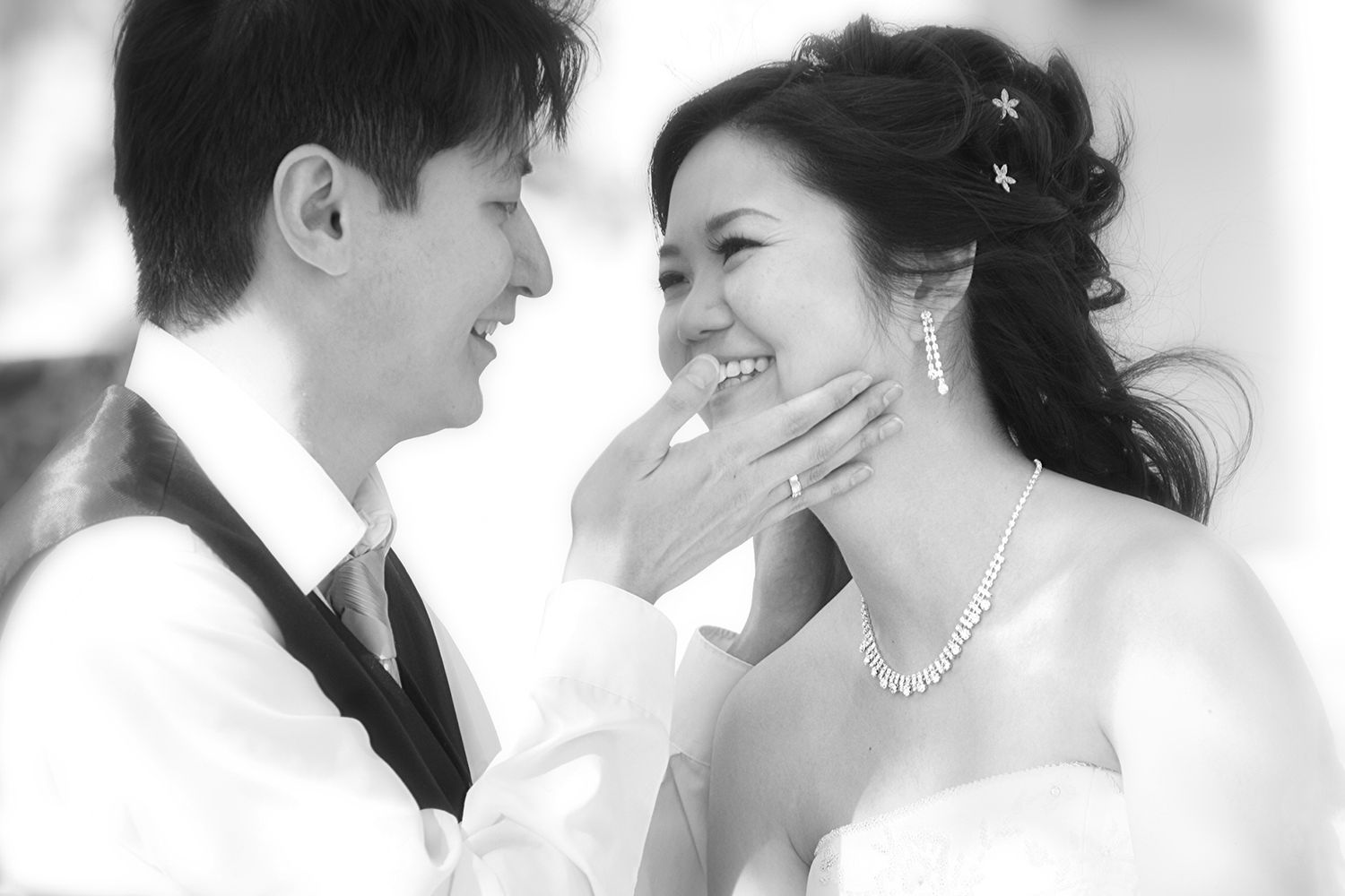 Joyful Asian bride and groom sharing a happy moment in black and white.