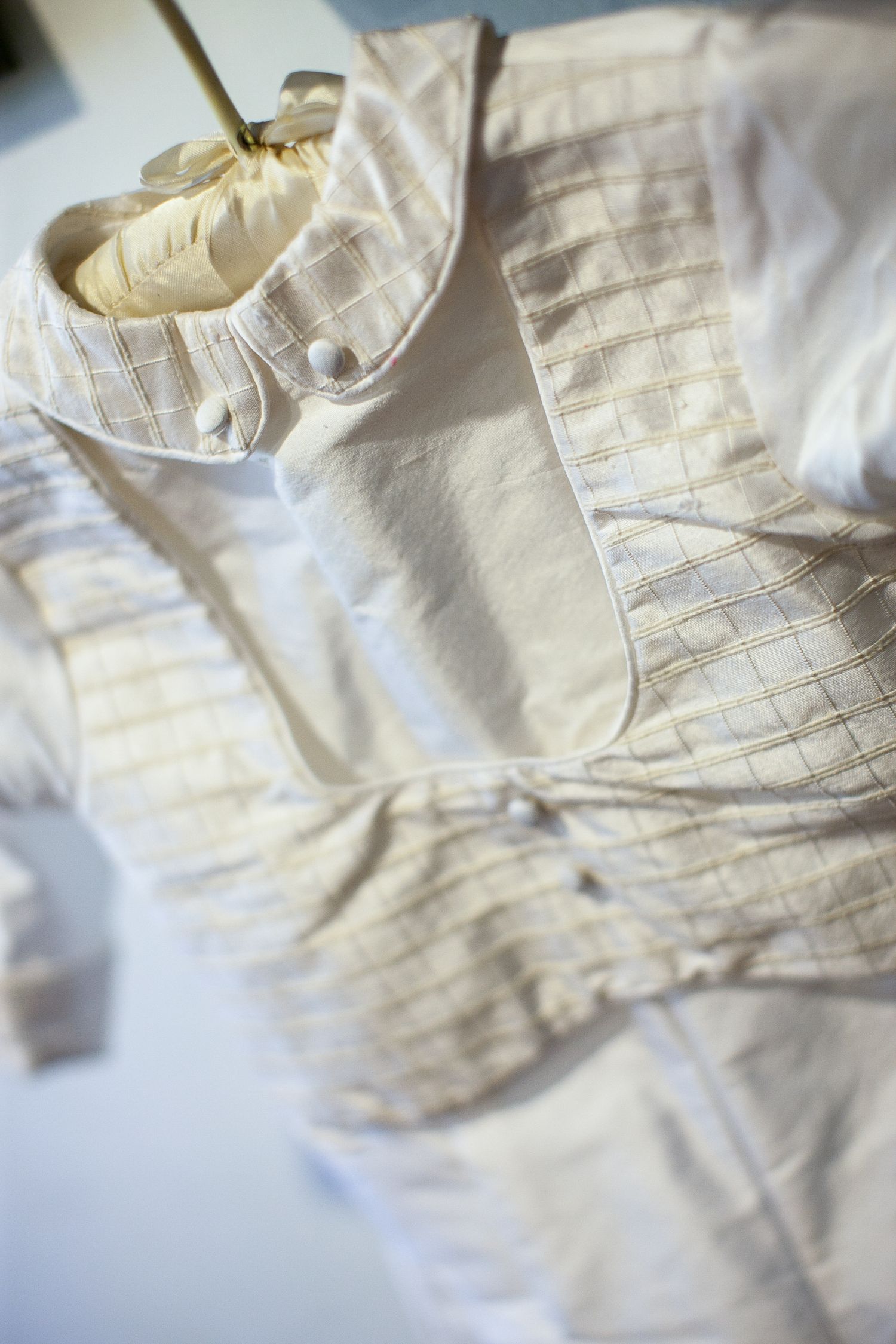 Elegant white and gold checkered vest with button details displayed on a hanger for a formal occasion.