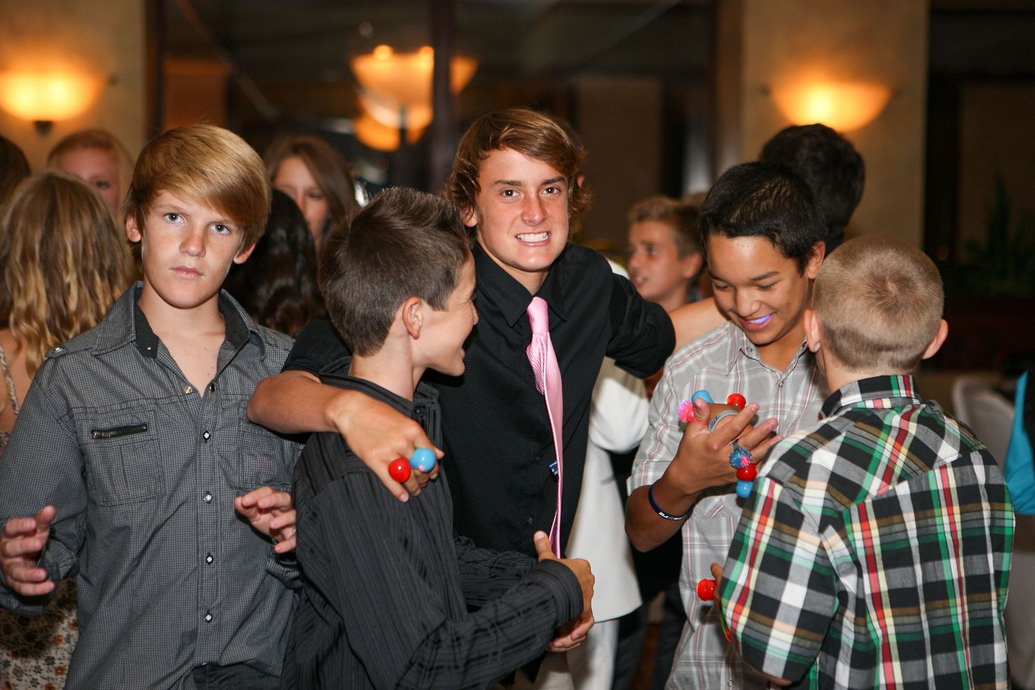 Group of young boys in dress clothes socializing at a formal event or party indoors.