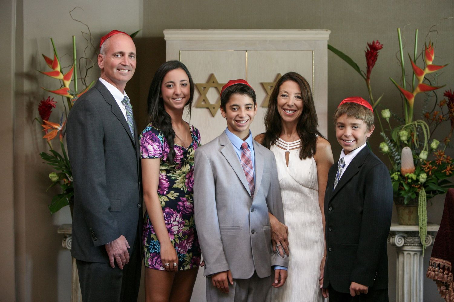Family of five posing together at a Bar Mitzvah celebration with Star of David decor in background.
