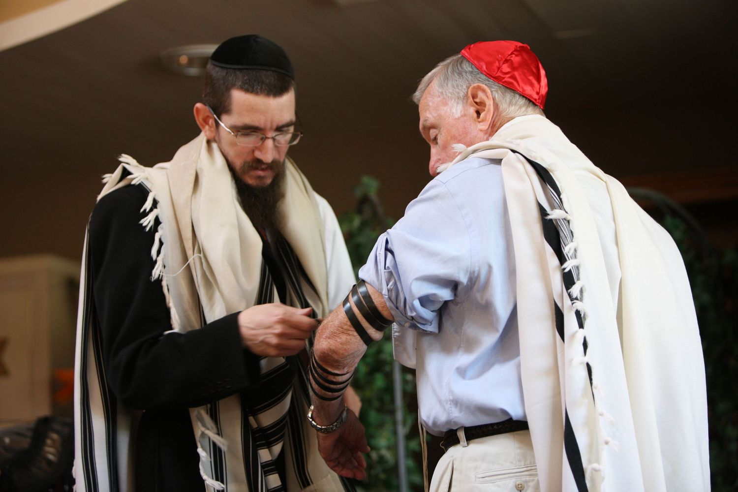 Two Jewish men wearing tallitot and tefillin during a religious prayer ceremony or Bar Mitzvah celebration.