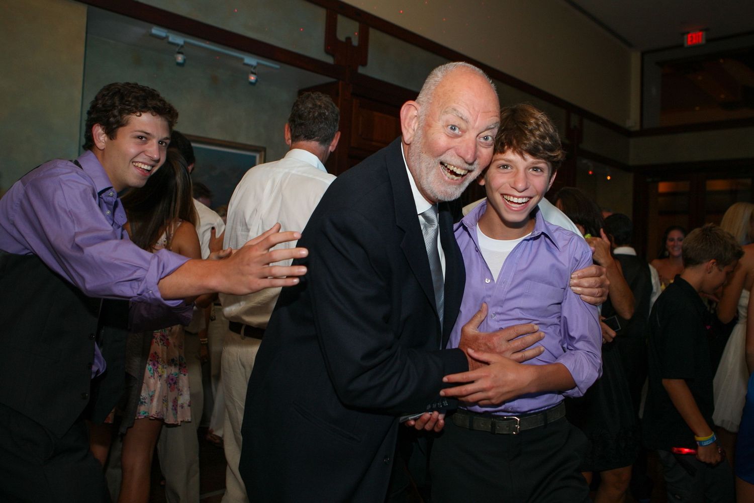 An elderly man joyfully dances with a young boy at a formal party event.