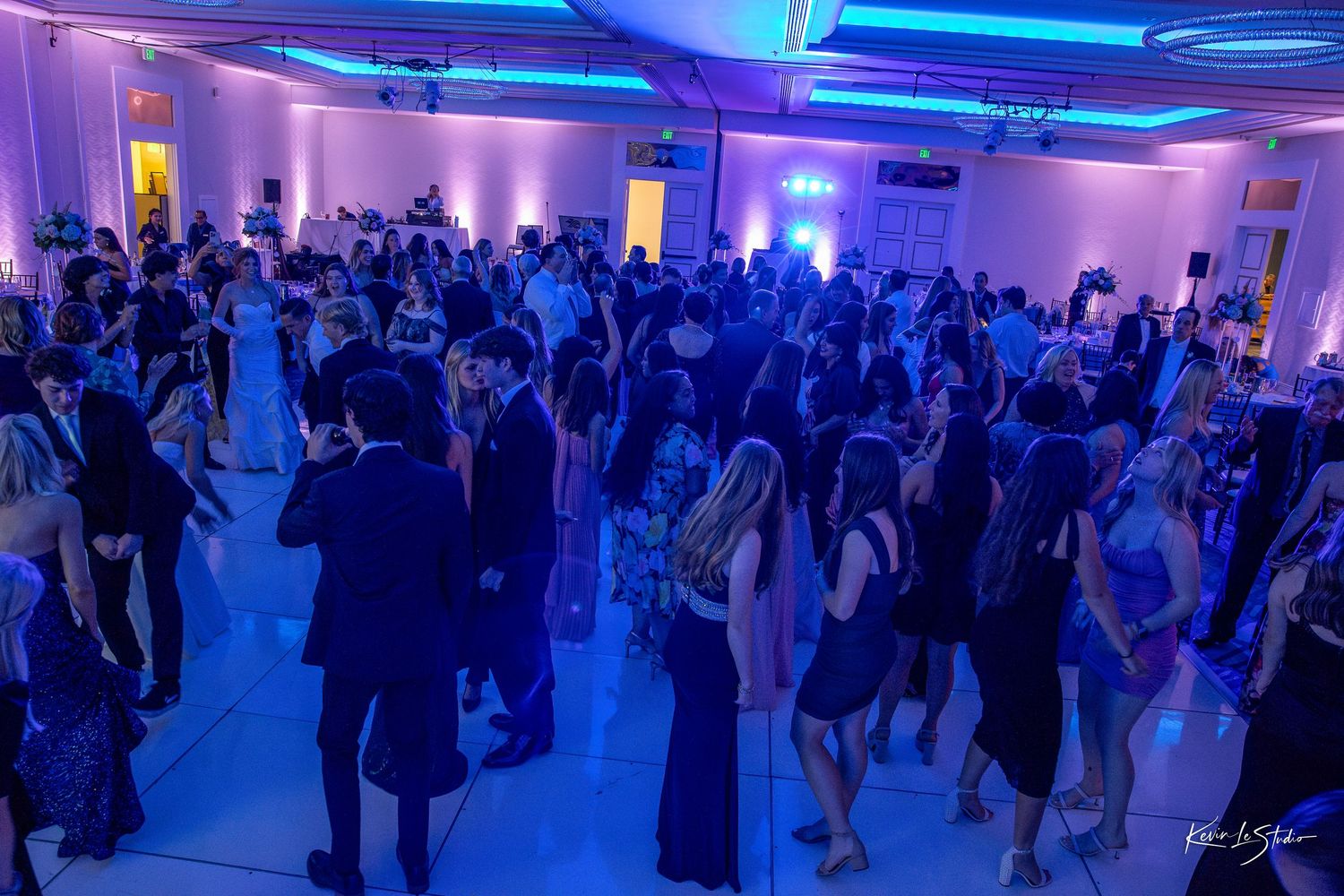 Elegant ballroom filled with guests dancing under blue and purple uplighting at a formal evening event.