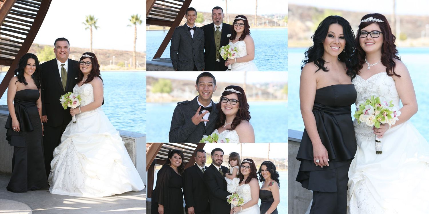 Wedding party poses by waterfront venue, bride in white gown with bouquet, groom in tux, bridesmaids in black dresses.