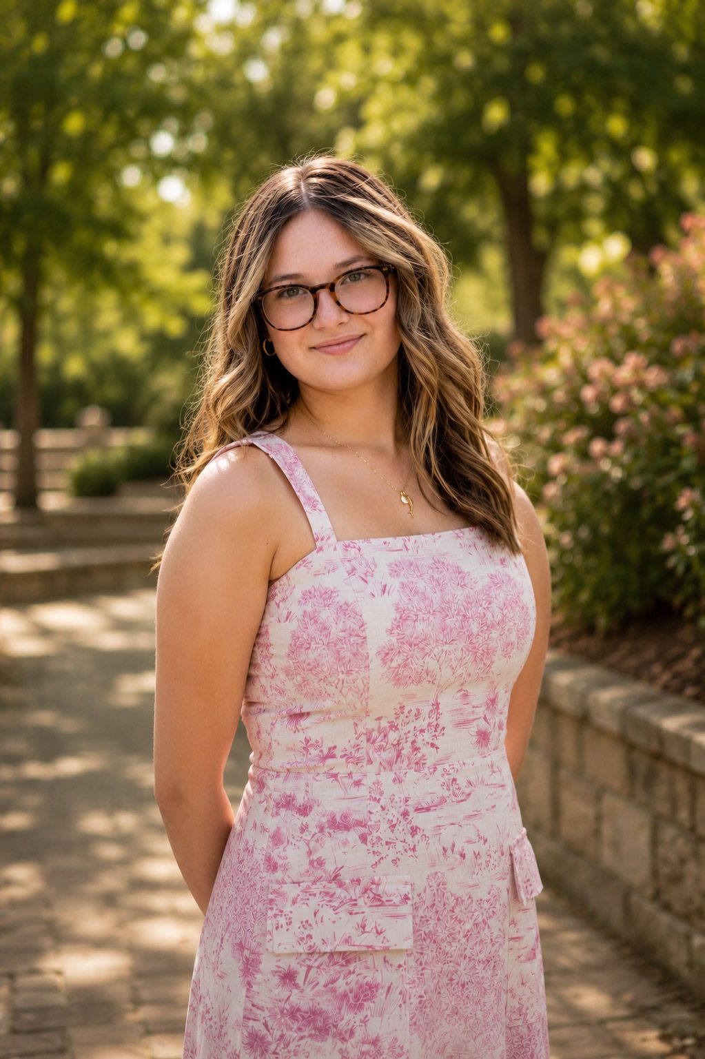 Woman in a pink dress posing for a professional portrait with soft natural lighting outdoors.