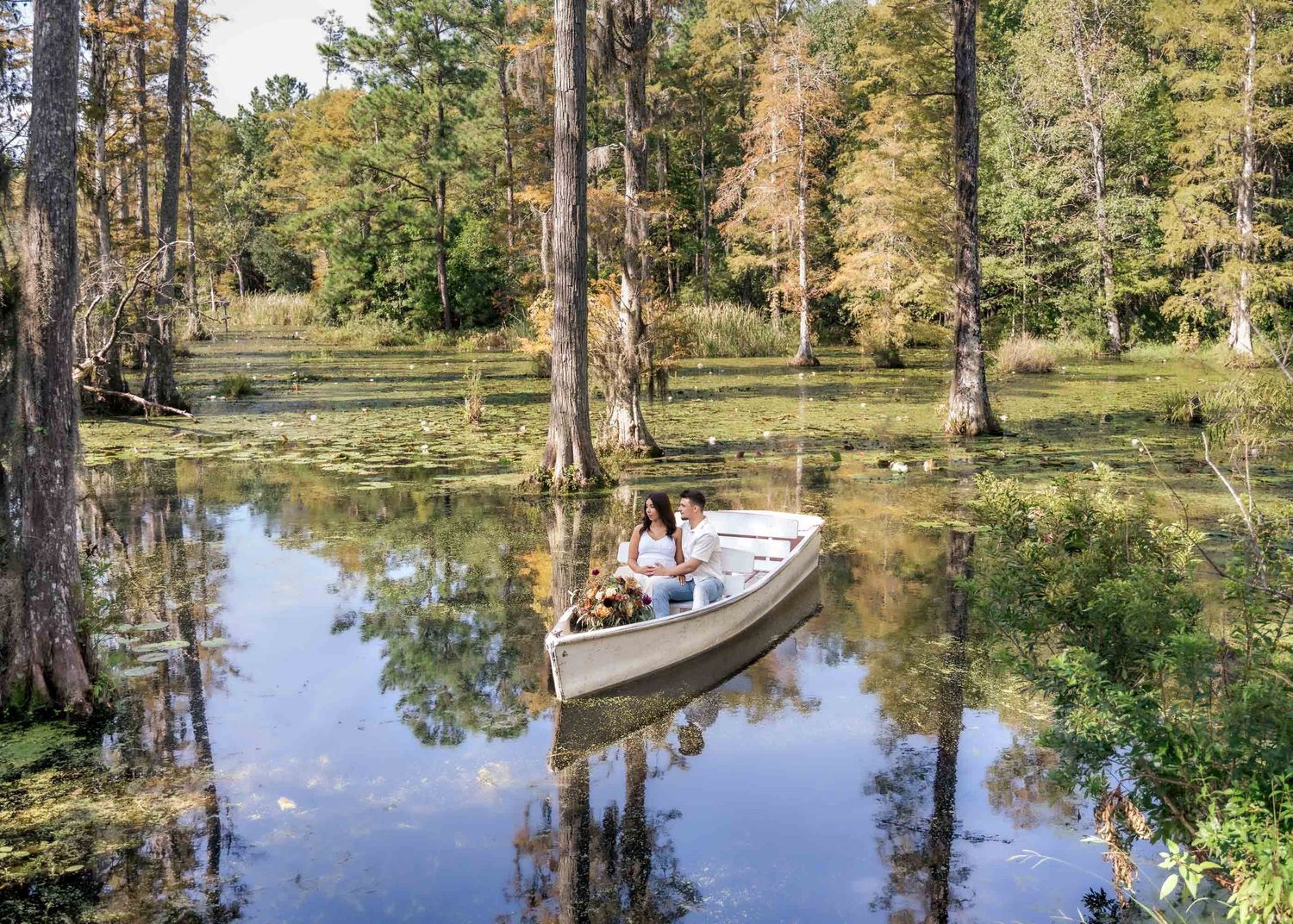 Cypress Gardens. Couple sharing intimate moment in white rowboat on serene cypress tree-lined swamp.