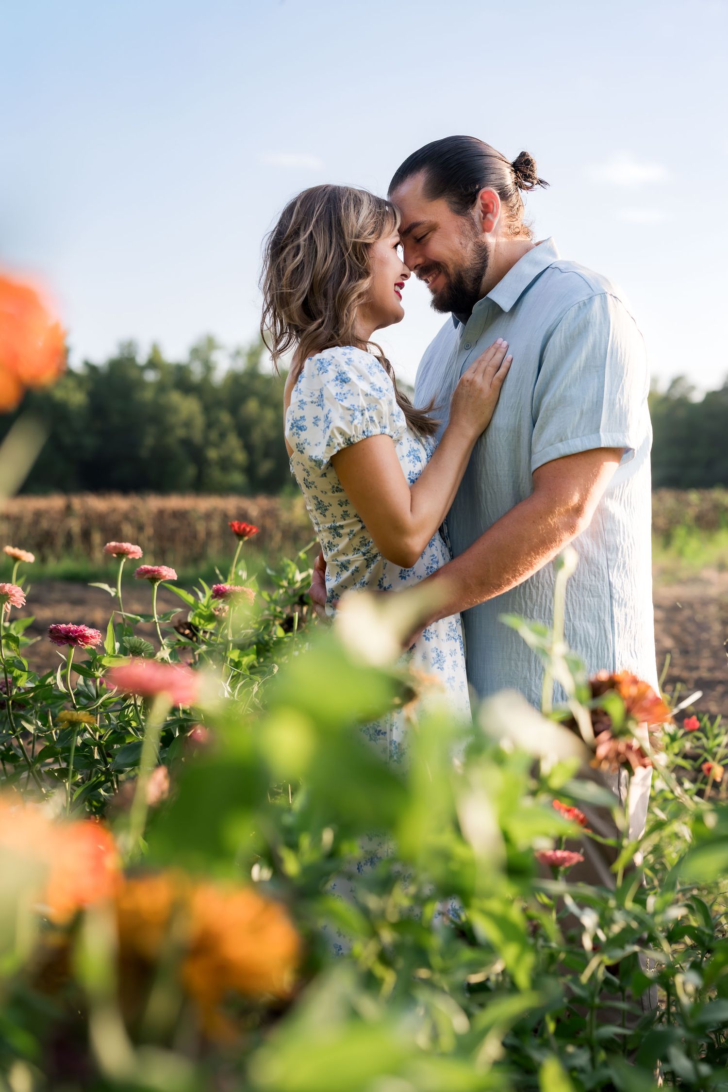 Couple sharing a romantic moment surrounded by colorful blooming flowers in a sunny garden field.