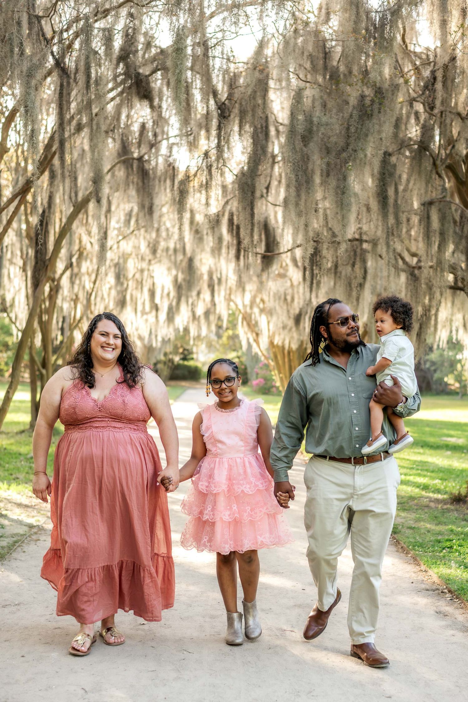Hampton Park. Happy family walking on tree-lined path with Spanish moss, dressed in pink and green.