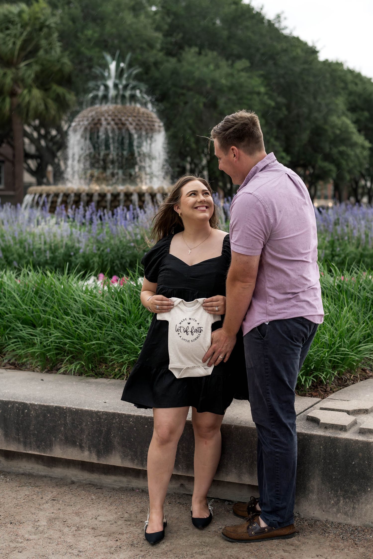 Pineapple Fountain. A smiling couple stands near a pineapple fountain, the woman holding a decorative tote bag outdoors.