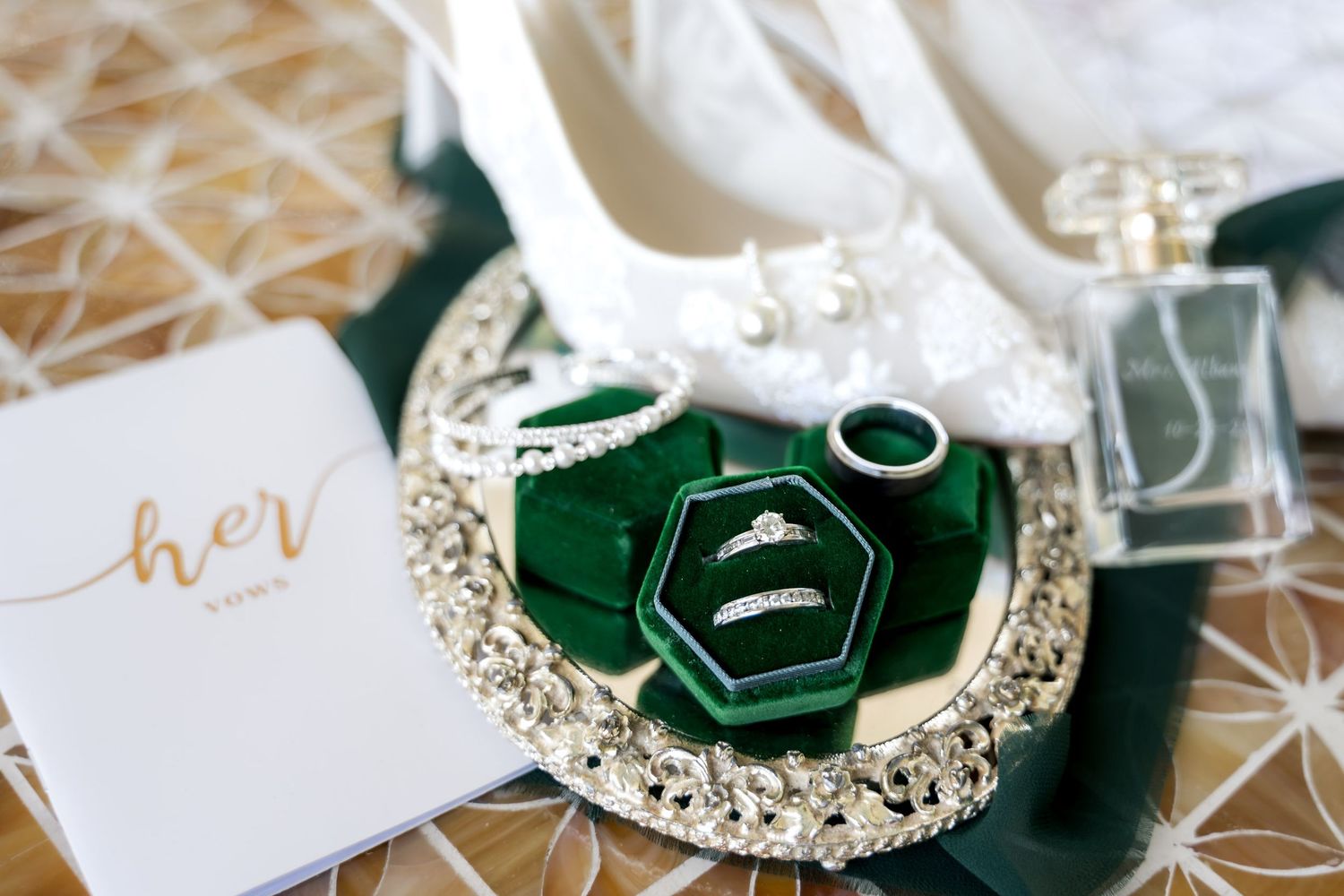 Dunes West Golf and River Club. Wedding flat lay featuring diamond rings in green velvet box, white heels, perfume, and bridal accessories.