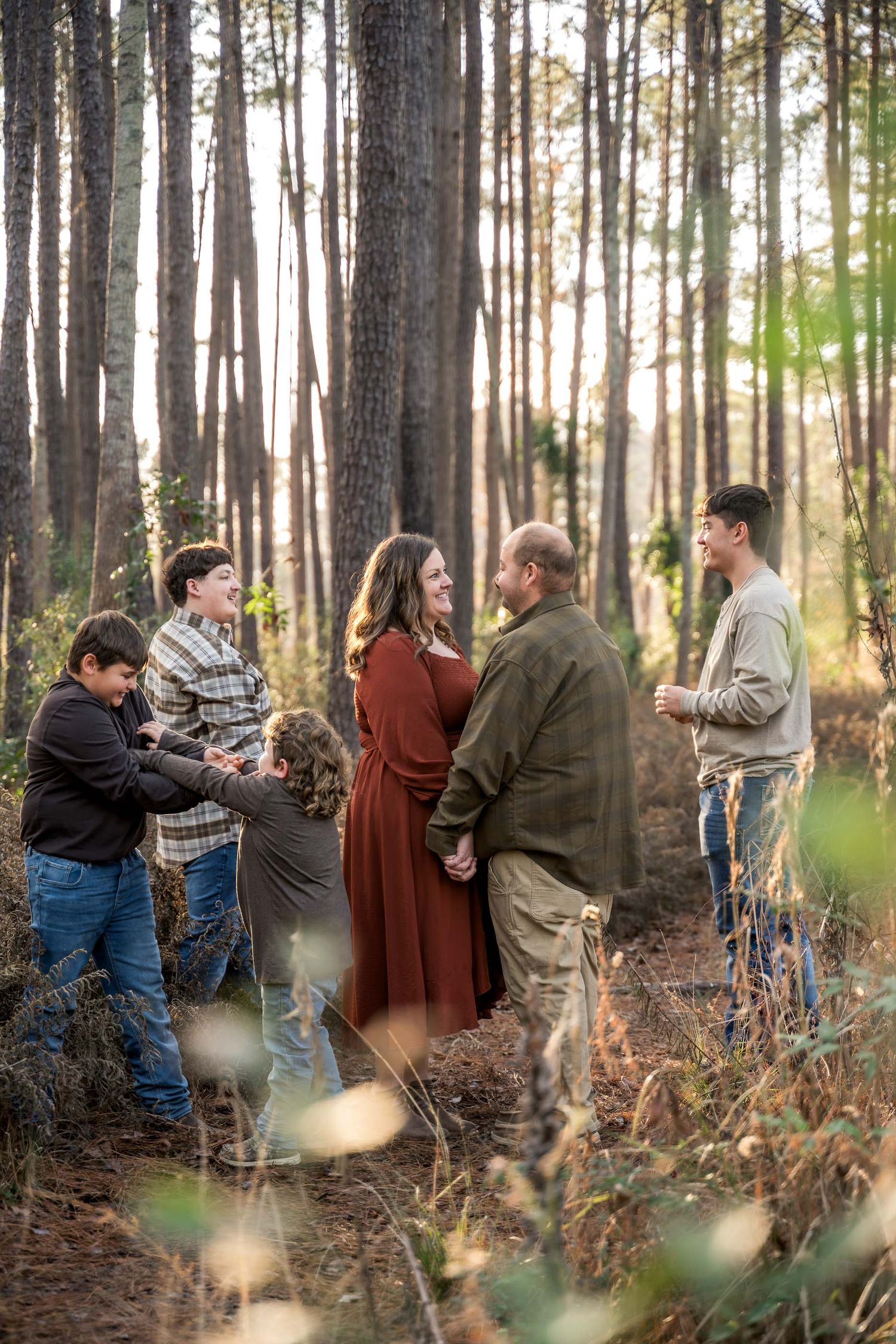Moncks Corner.Family of six sharing a joyful moment together in a sunlit pine forest.
