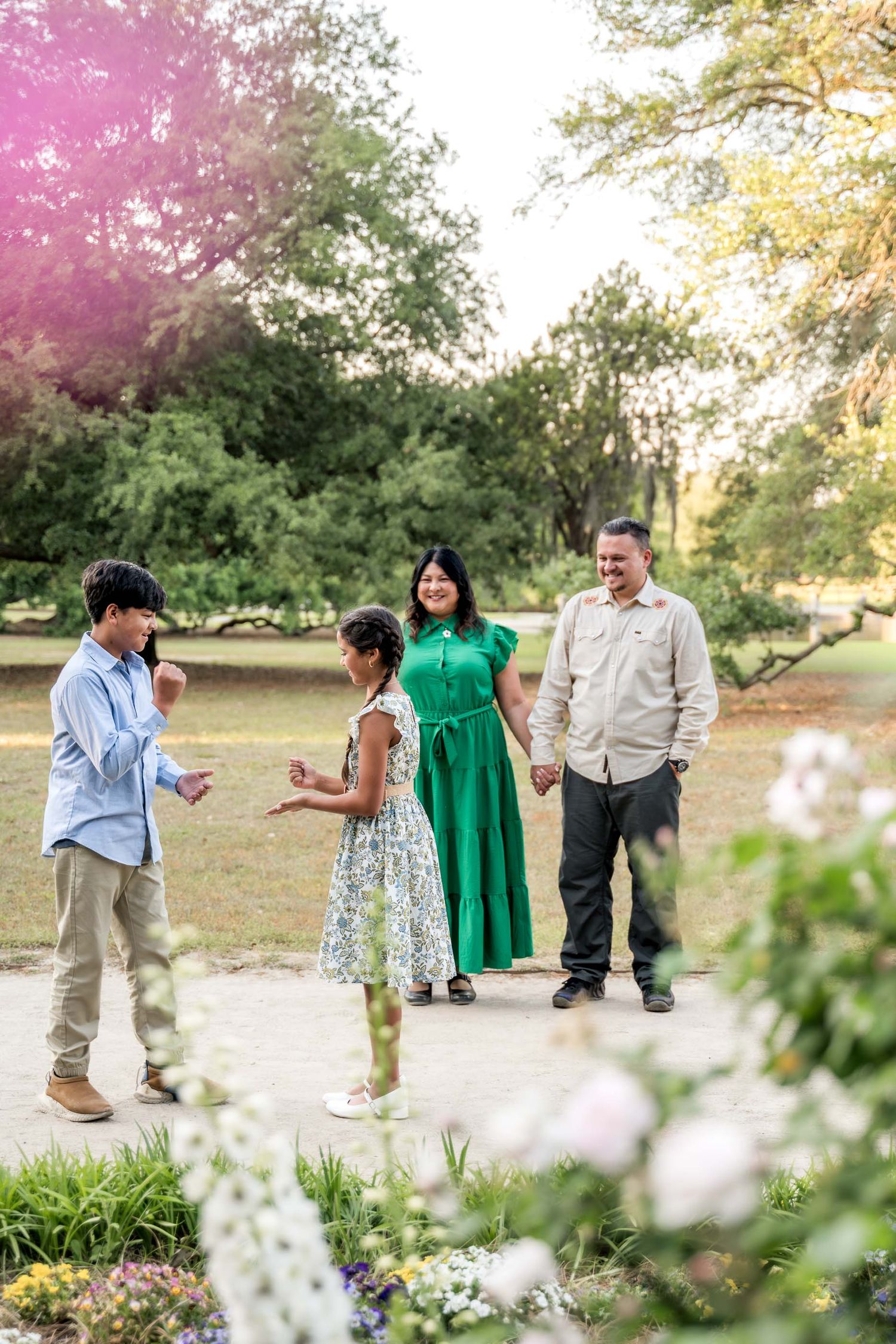 Hampton Park. Happy family of four enjoying a sunny day in a lush green park together.