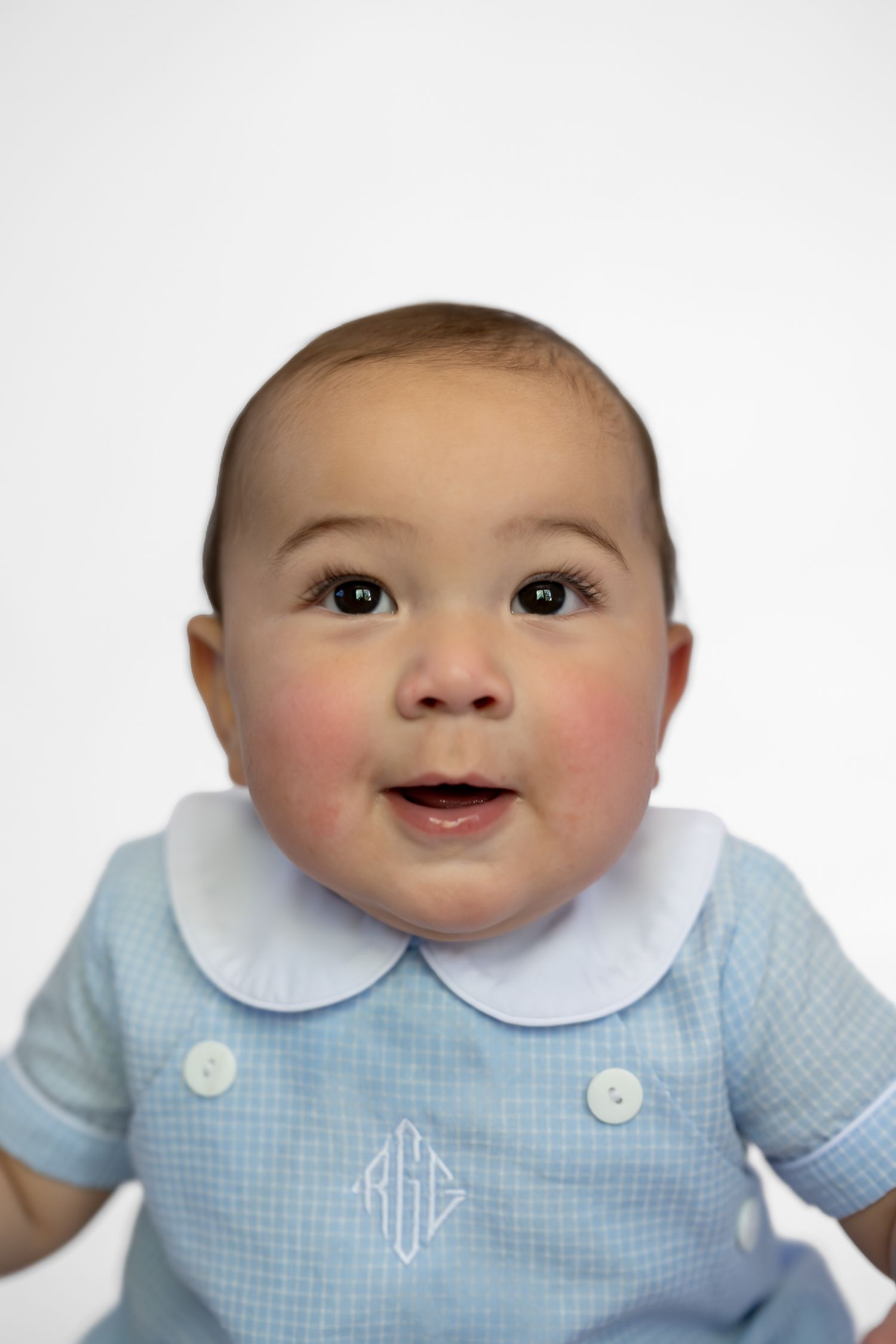 Smiling baby in blue gingham monogrammed outfit with white Peter Pan collar against white background.
