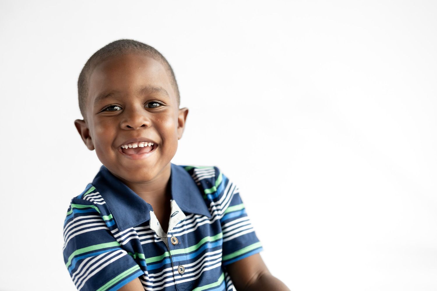 Smiling young Black boy wearing a blue striped polo shirt, posed against a white background.