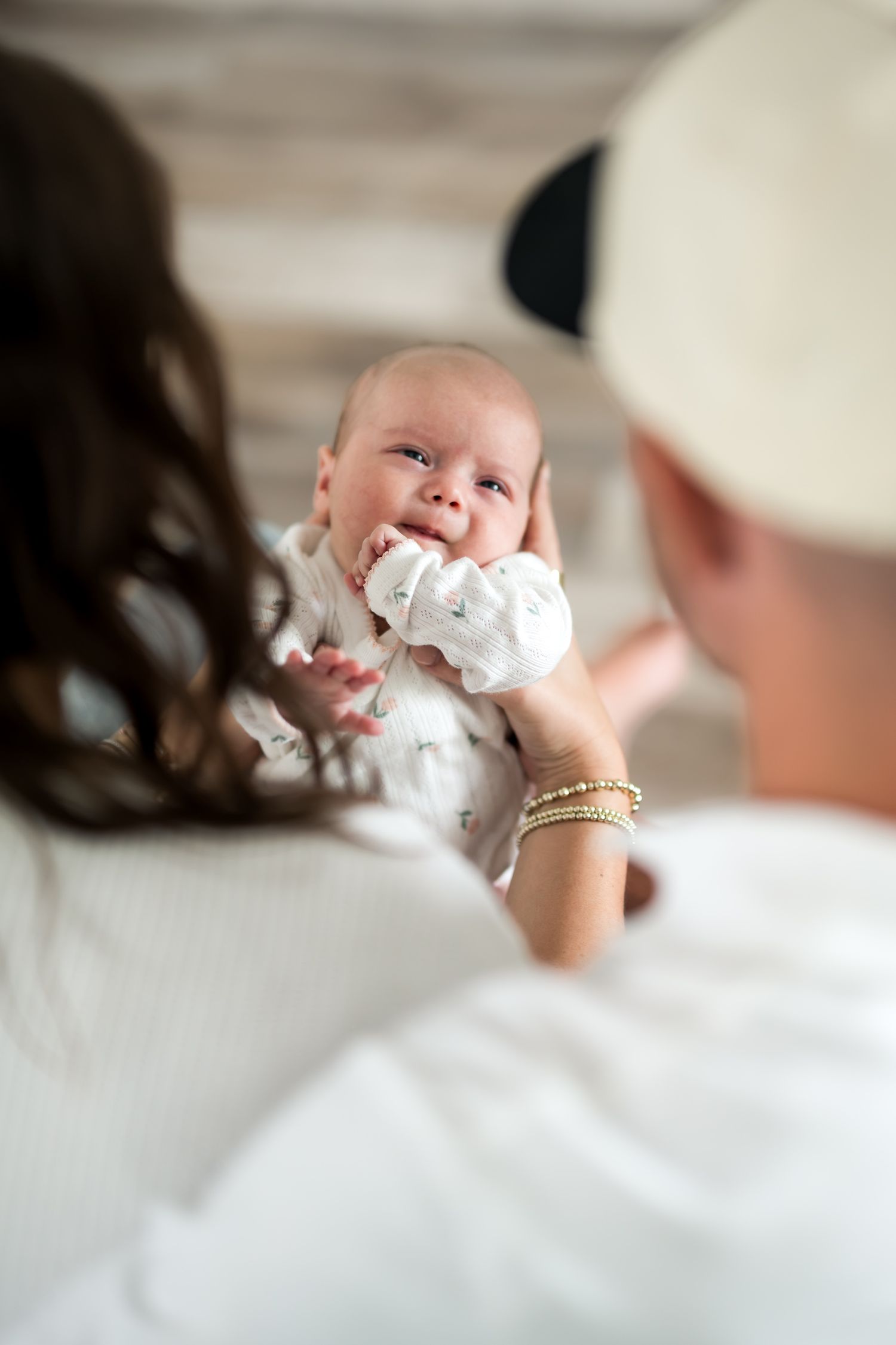 Parents lovingly cradling their newborn baby dressed in white, sharing a tender family moment together.