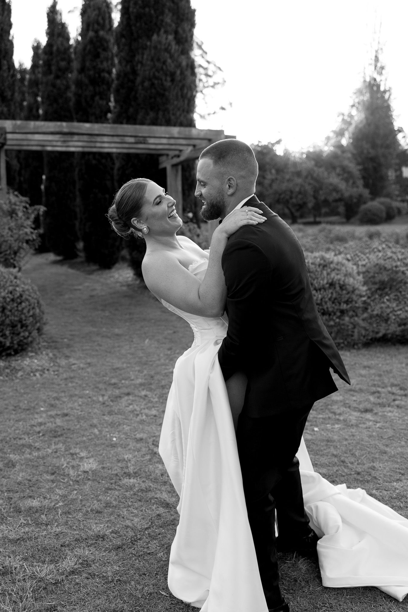 A romantic black and white photo series shows a couple in wedding attire dancing together outdoors.