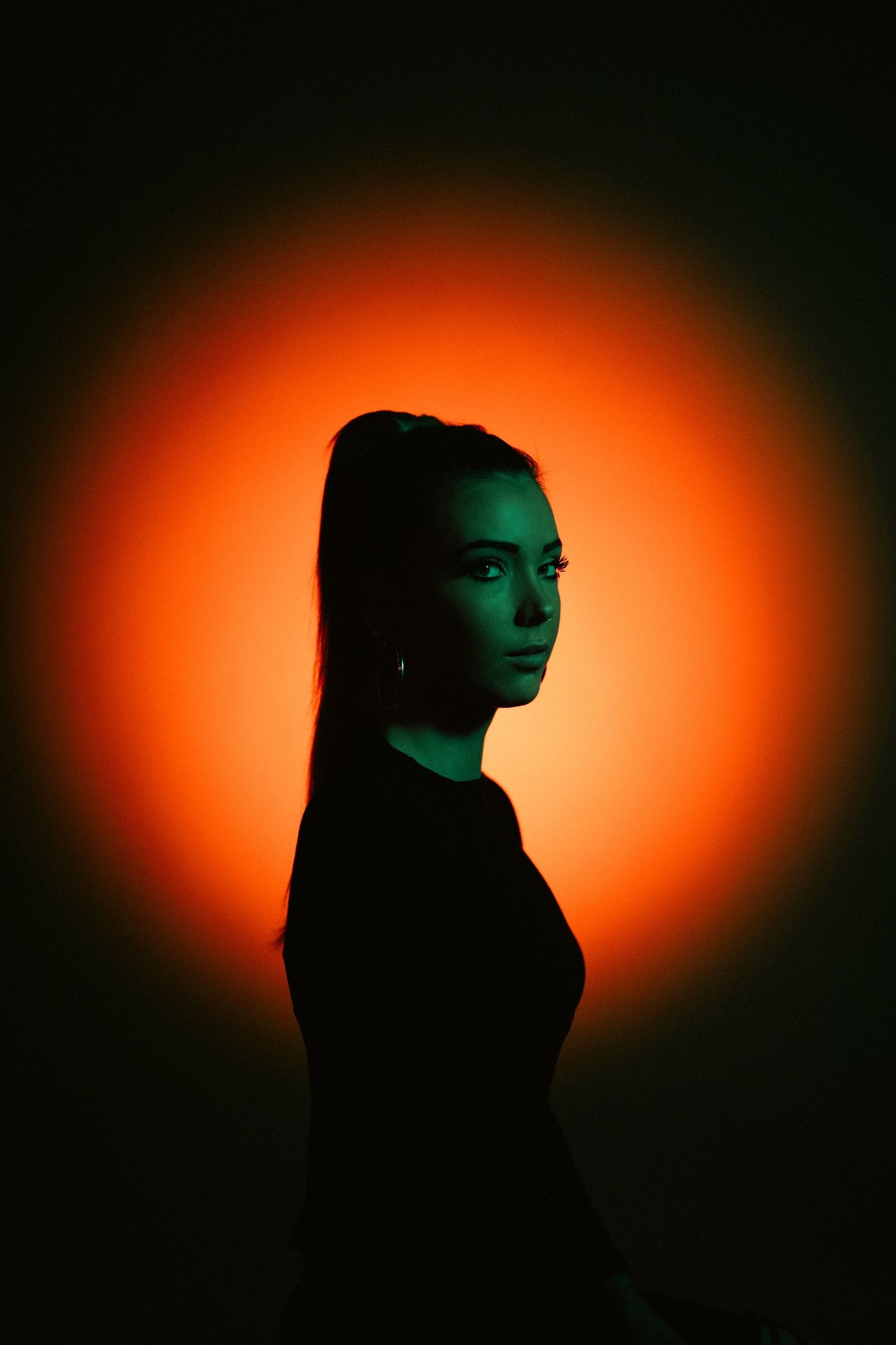 A series of dramatic silhouette portraits against a glowing orange and green gradient background creates an artistic sequence.