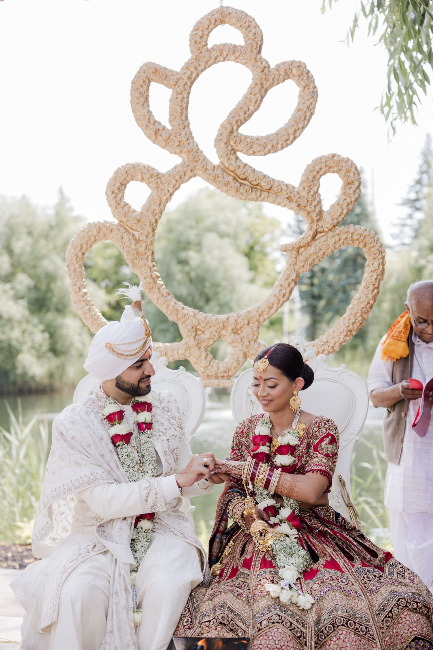 Traditional Indian wedding ceremony with couple seated under ornate gold heart-shaped mandap decorations.