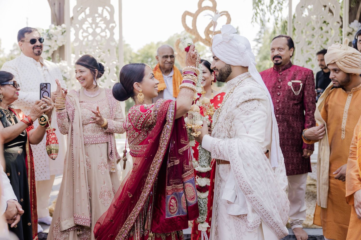 Traditional Indian wedding ceremony with guests celebrating and throwing colorful flower petals in the air.