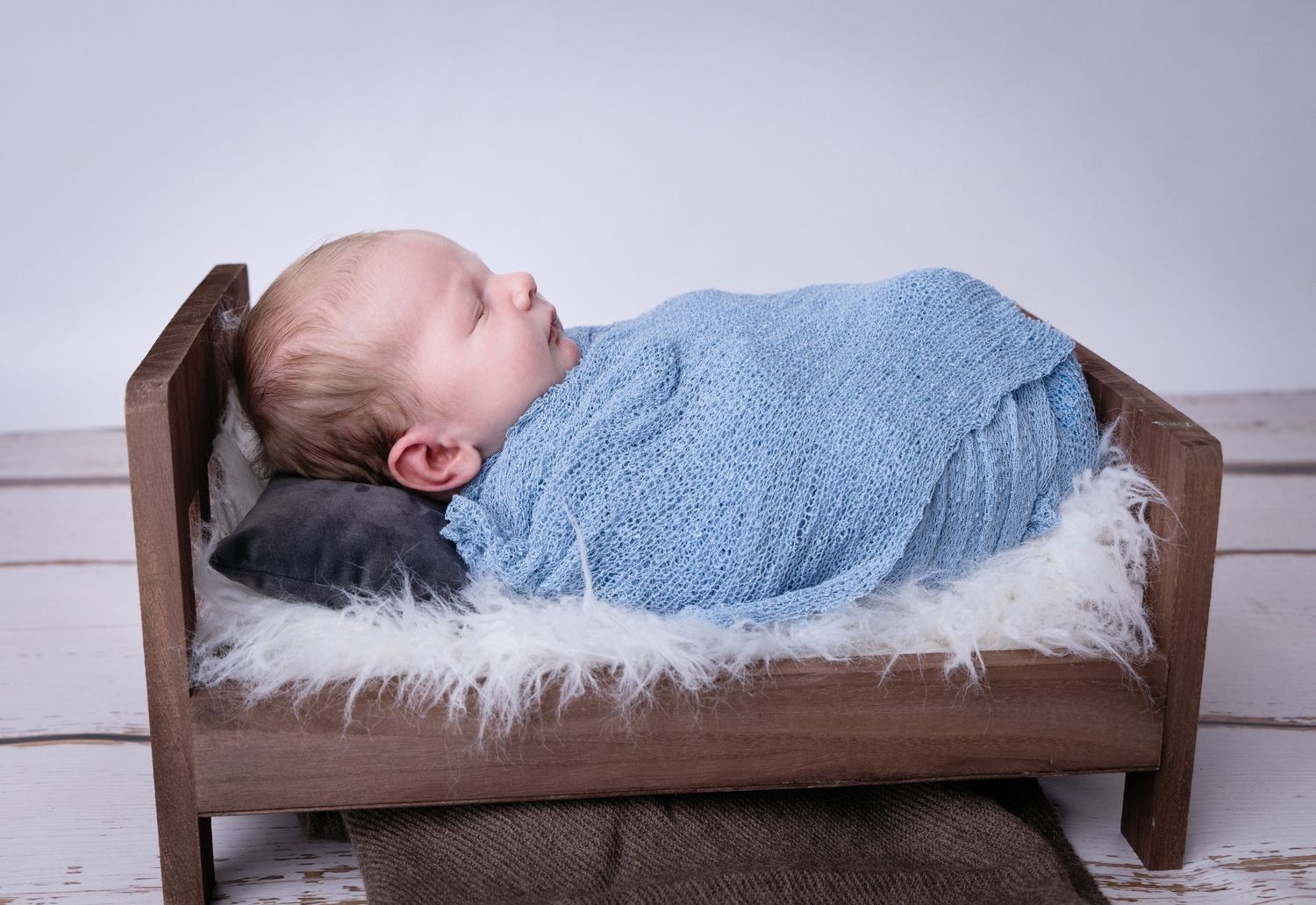 A series of six photos showing a sleeping baby on a rustic wooden bed with blue and white blankets.