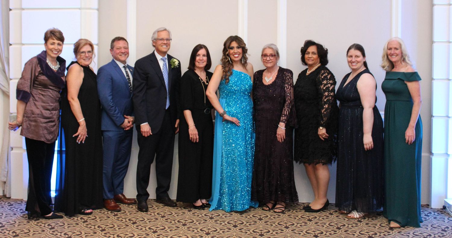 A formal group photo of people dressed in elegant evening attire at an event.