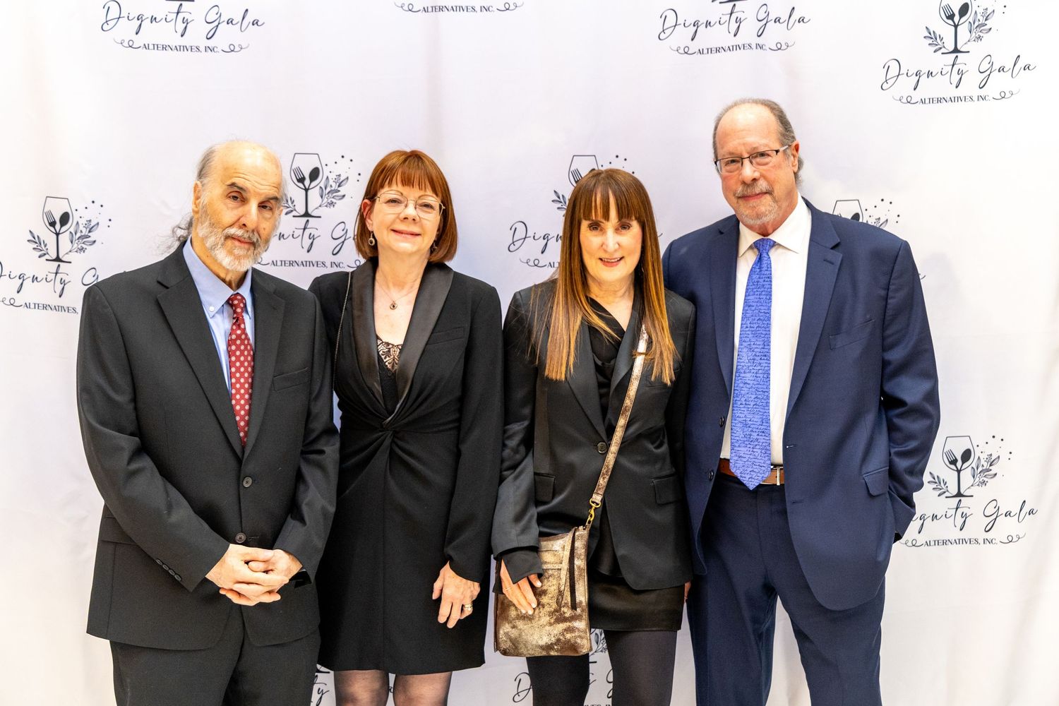 Group of people in formal business attire standing together against a white backdrop with logos.
