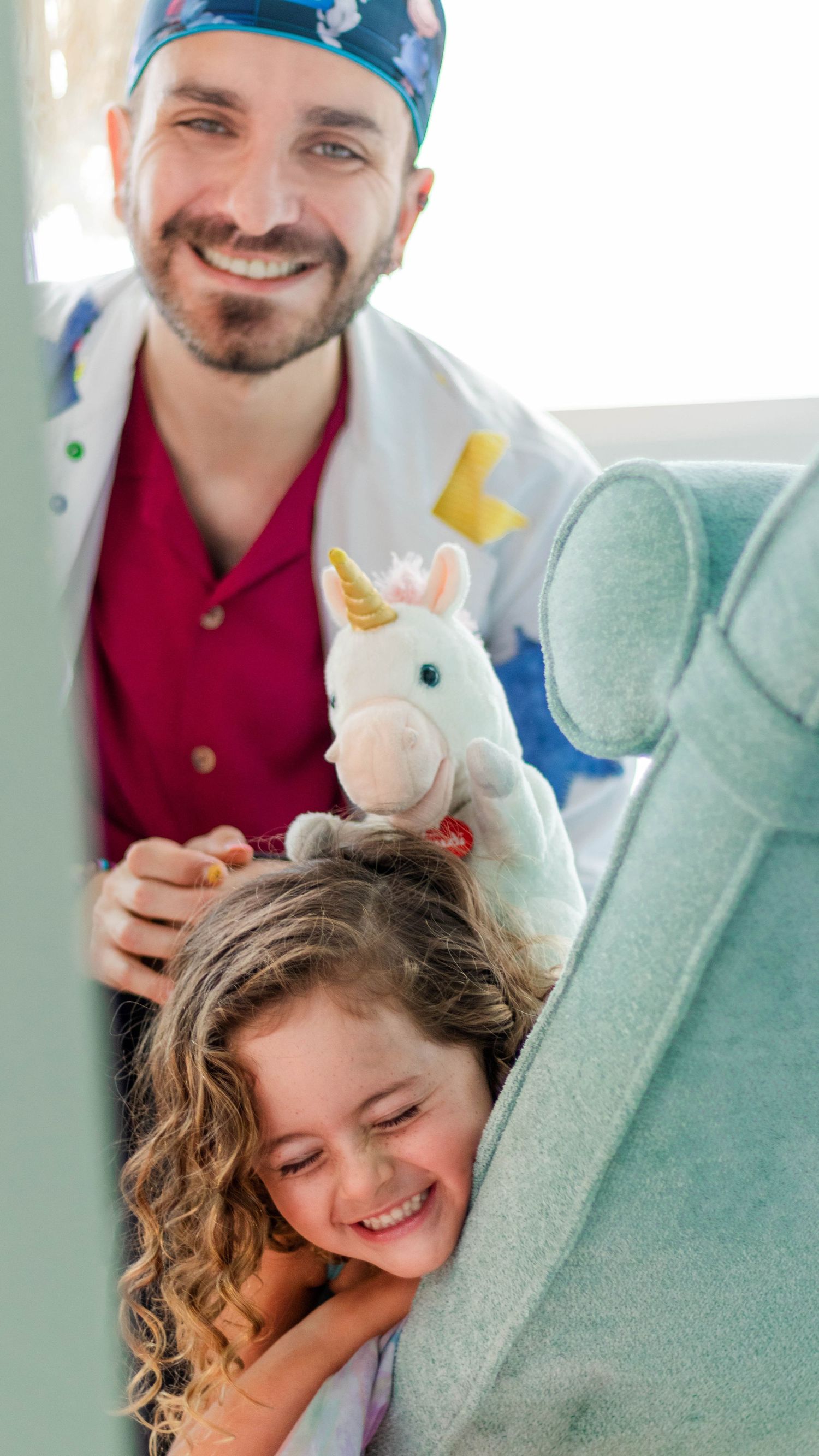 Playful moment in pediatric dentistry with stuffed unicorn toy and young patient.