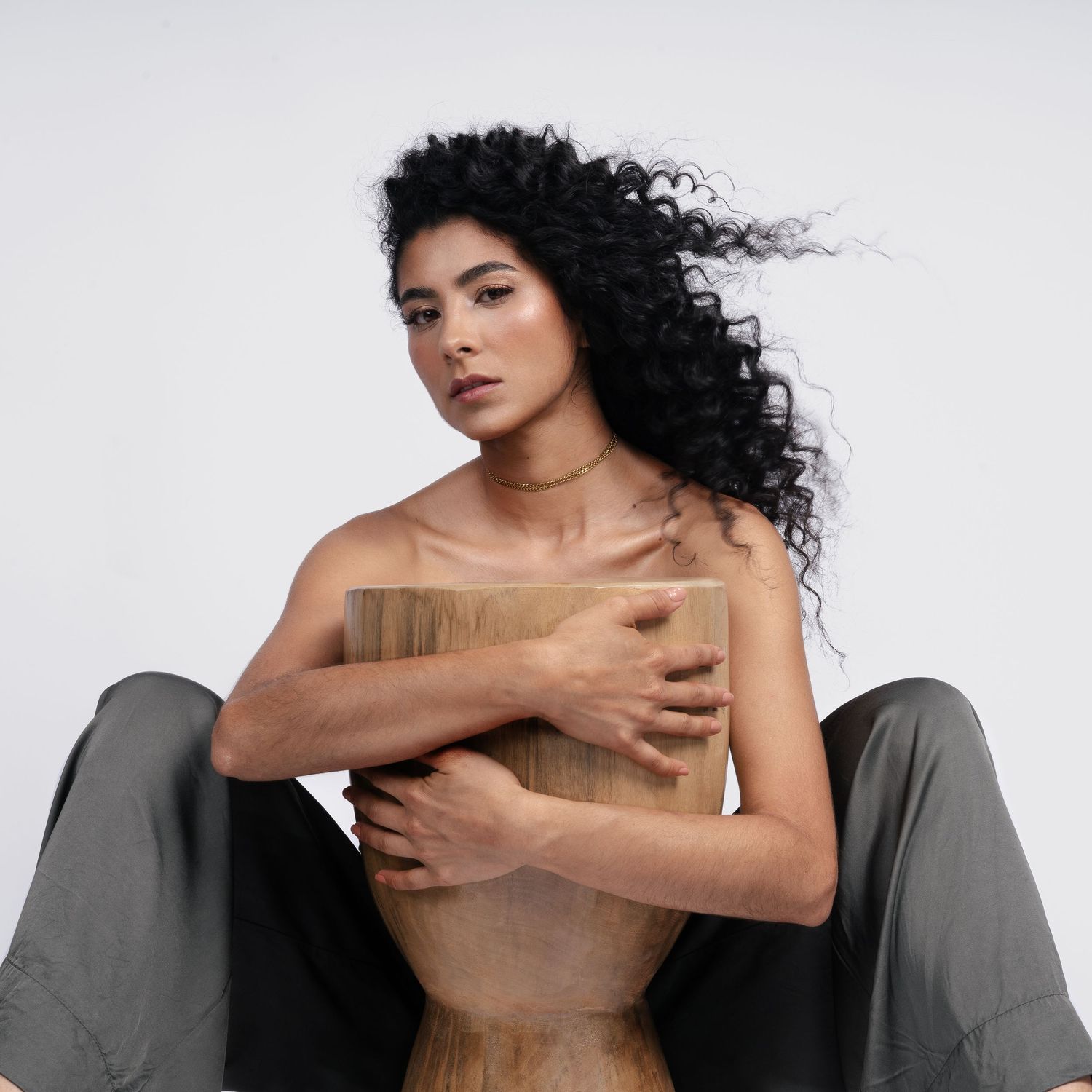 Artistic fashion portrait with flowing curls and draped fabric against white backdrop.