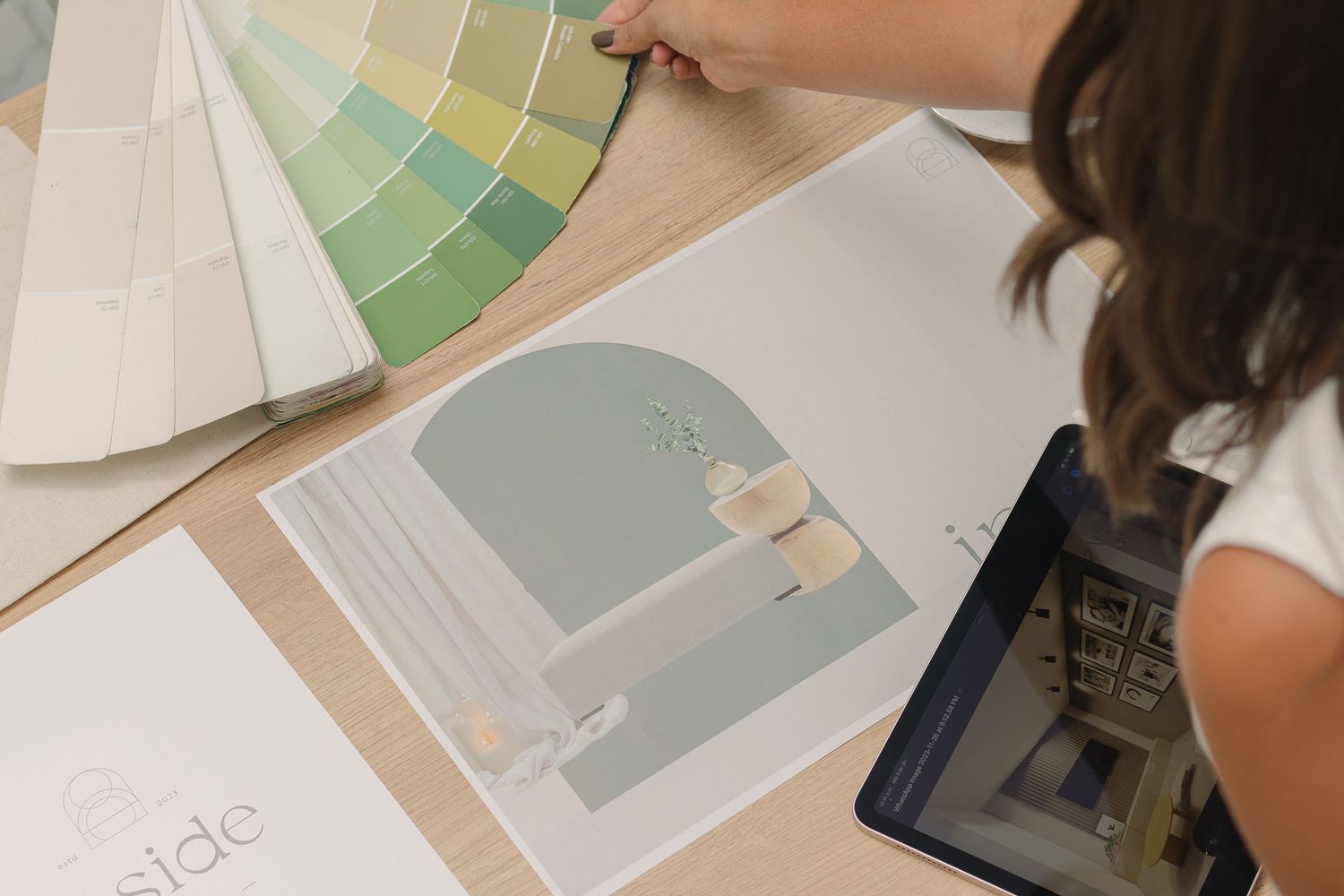 Designer reviewing paint swatches and interior design materials with digital tablet.