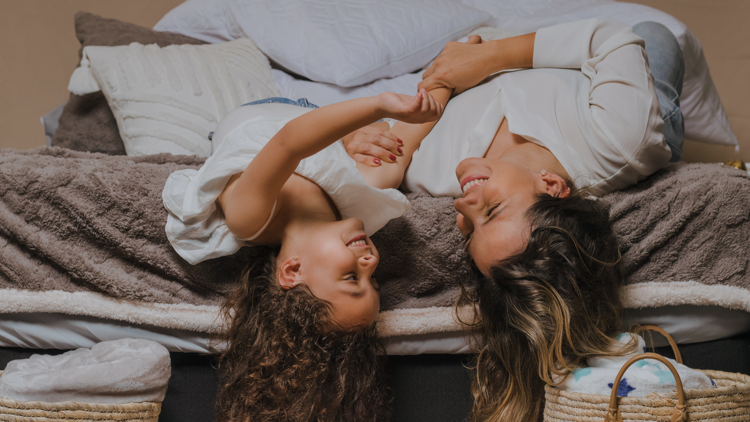 Two people lying down on a bed sharing a joyful moment together.
