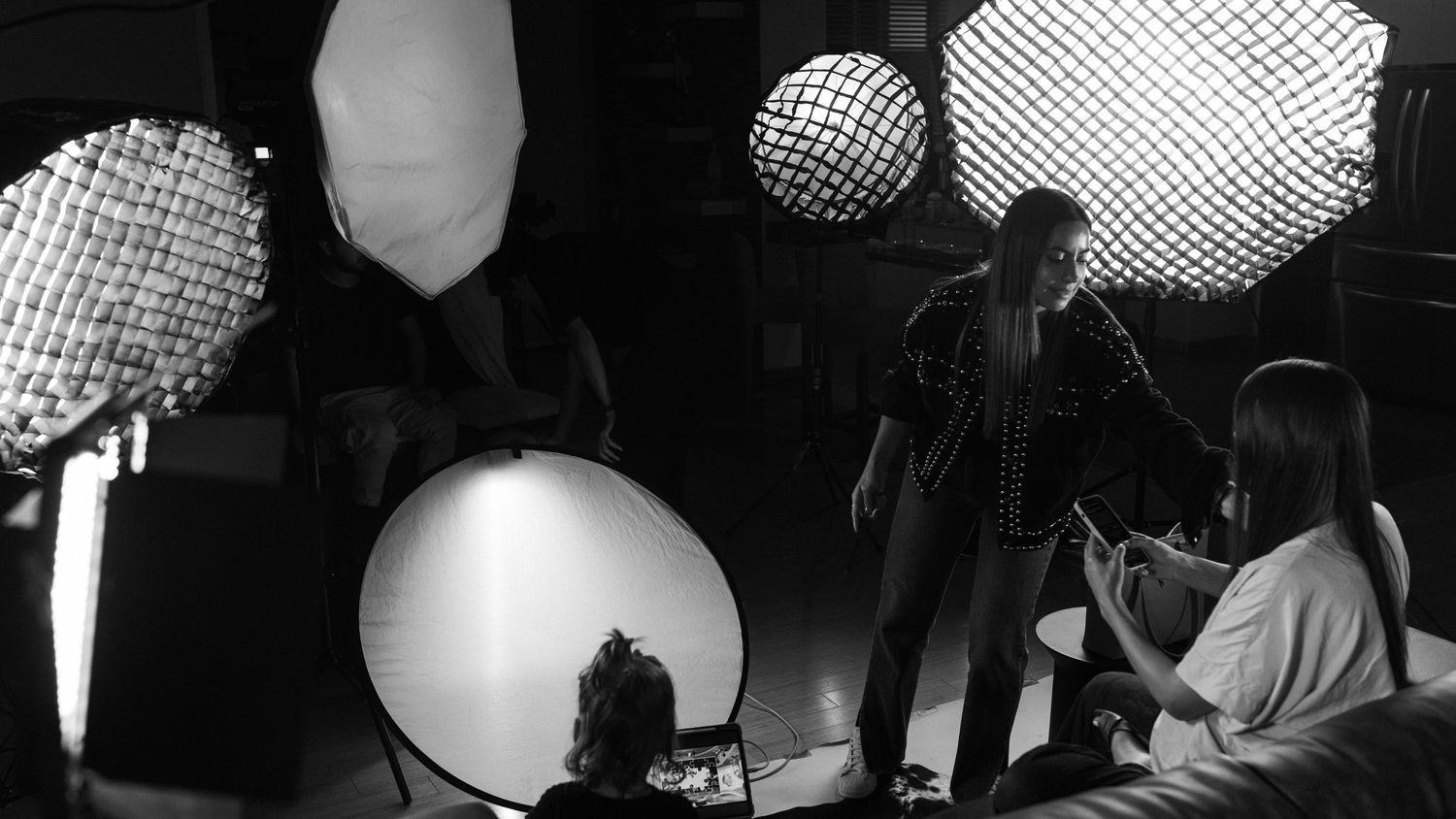 Black and white scene of performers on a stage with spherical lighting fixtures and geometric shapes in the background.
