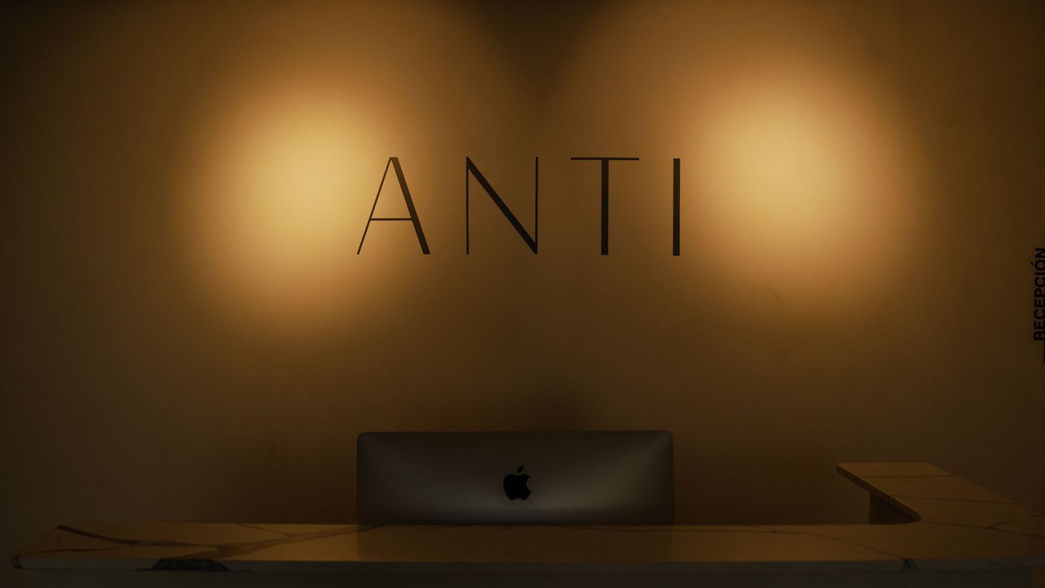 Modern office space with ANTI lettering and warm spotlights on wall.