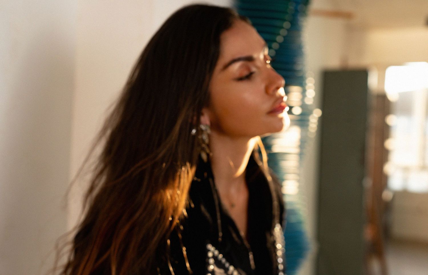 Portrait in dramatic lighting with sparkly black outfit and dangling earrings.