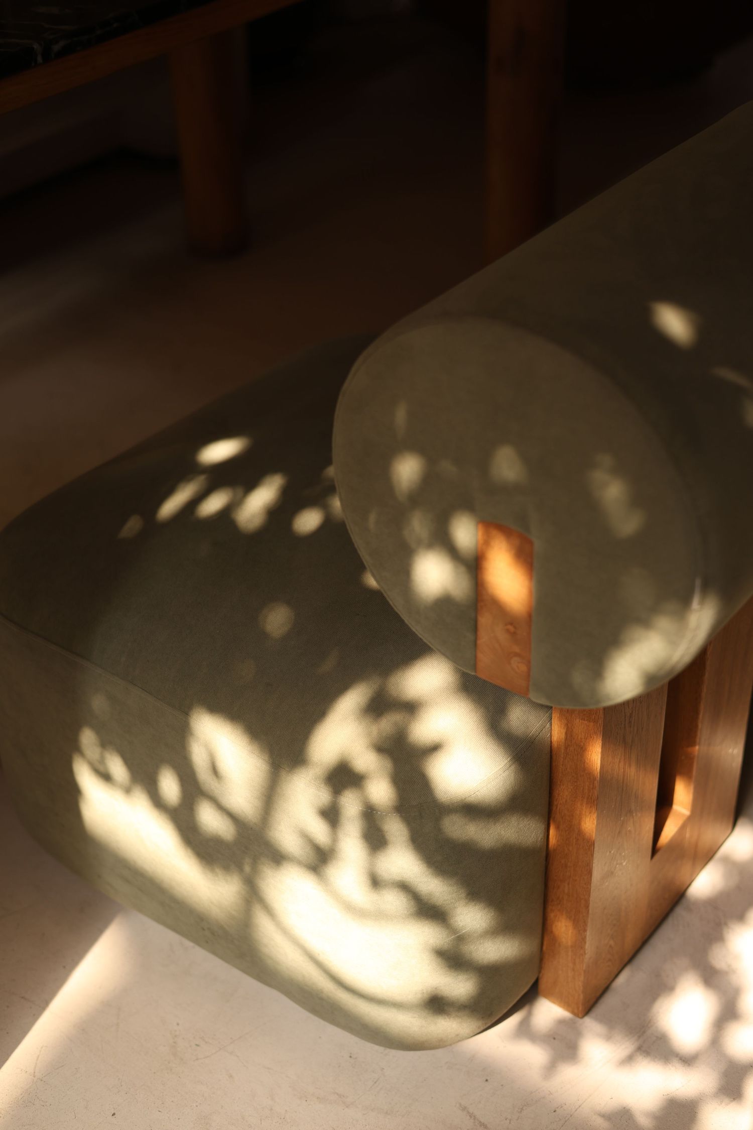 Dappled sunlight casting leaf shadows on minimalist furniture piece.