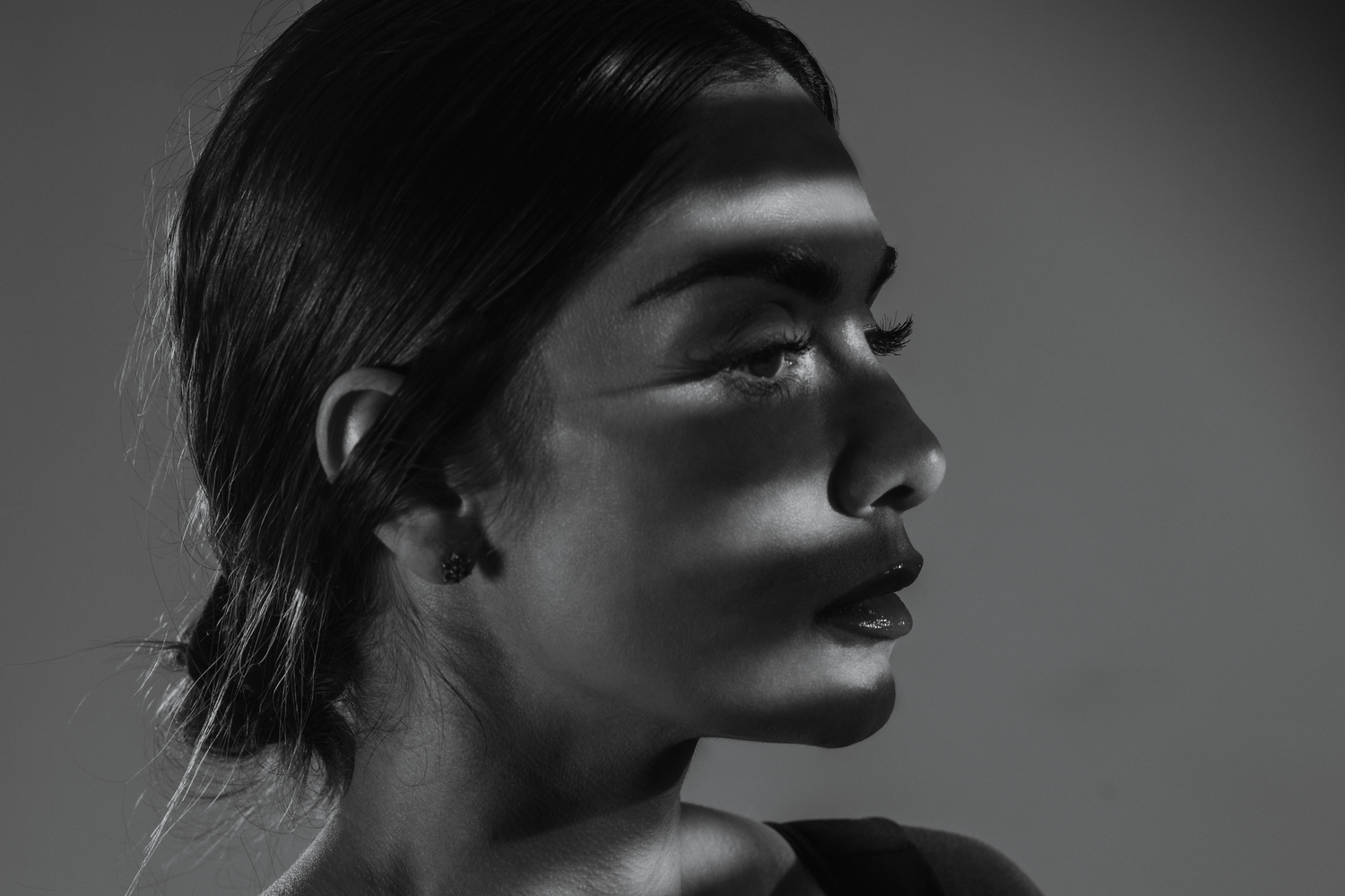 Dramatic side profile portrait in black and white with strong shadow contrast.
