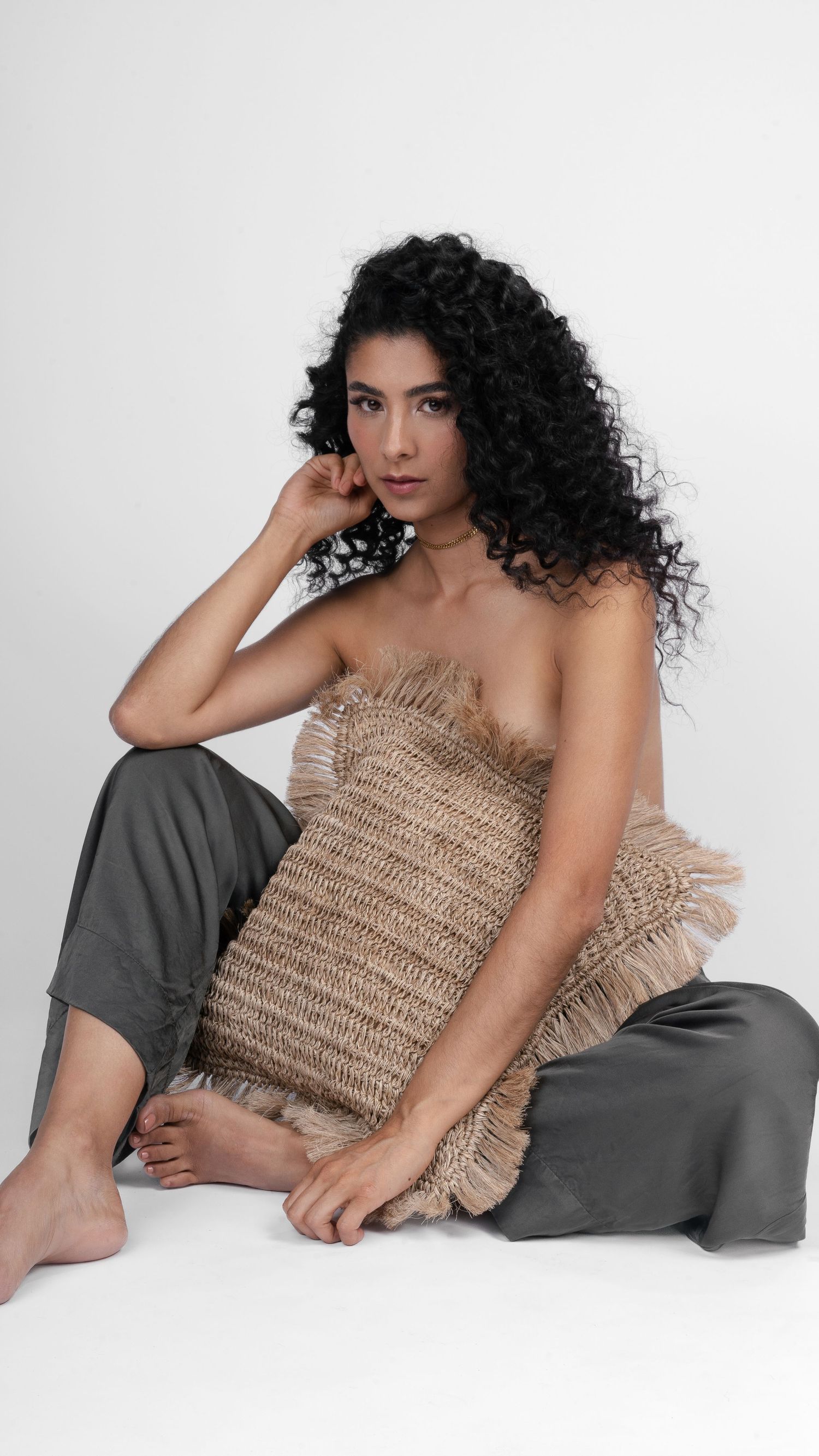 Modern fashion portrait featuring textured beige dress and flowing dark curls.