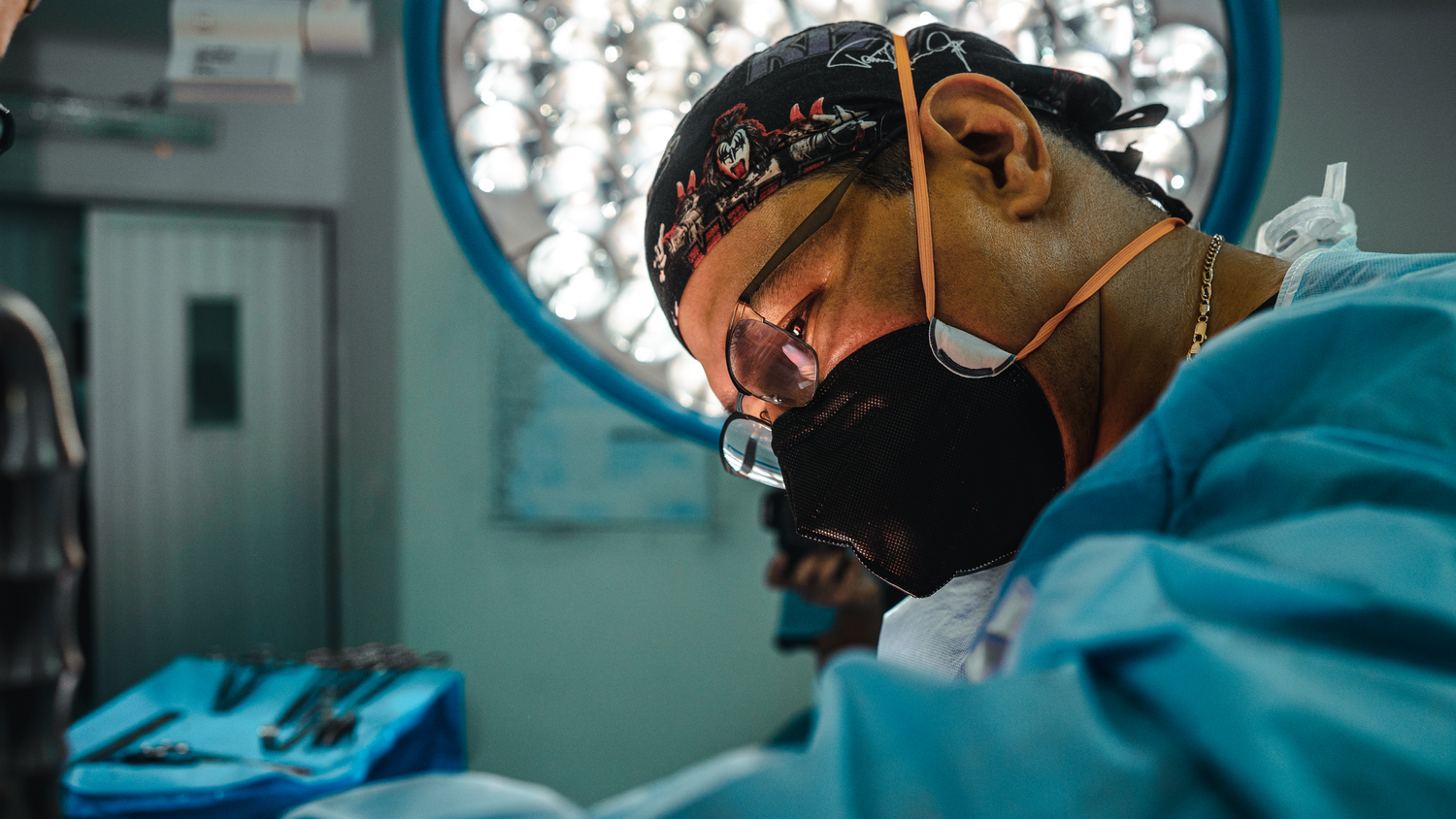 Medical professional focused during surgery under operating room lights.