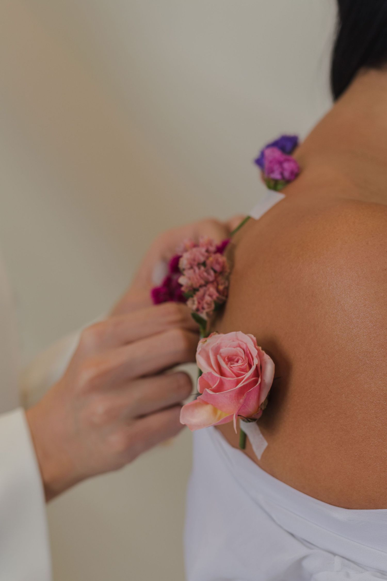 Delicate pink and purple flowers being arranged on white fabric in a close-up shot.